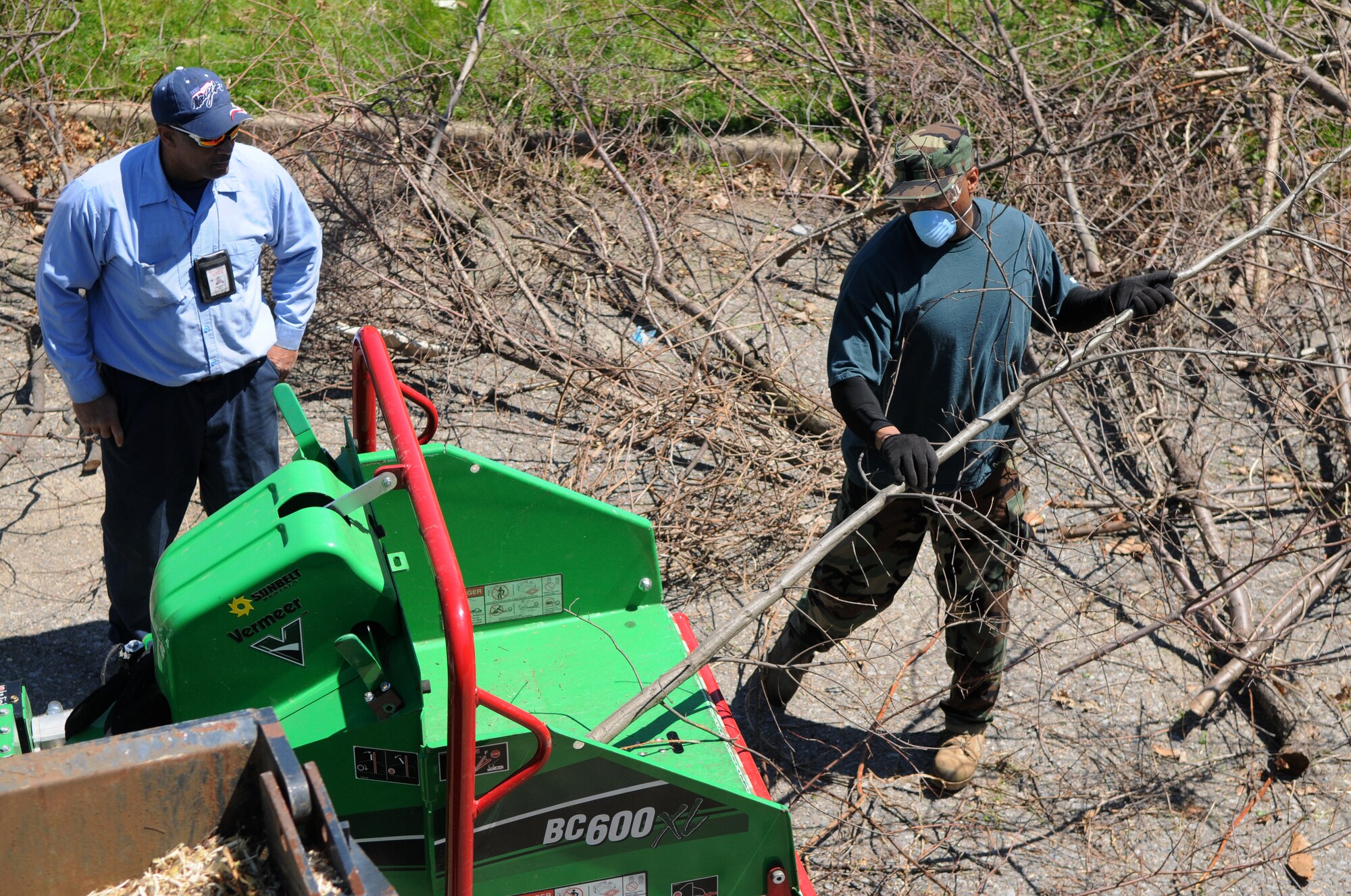 Mr. Nathaniel Hill, Saint Elizabeth’s Hospital gardener supervisor, observes Tech. Sgt. Edward Hill, Air Force Legal Operations Agency, send branches through the wood chipper April 17 at Saint Elizabeth’s Hospital, Washington, D.C. Volunteers from Bolling, including Coast Guard members, dedicated their time to help Saint Elizabeth’s clear out overgrown brush and vines, and pick up trash in preparation to restoring their cemetery. The cemetery is the final resting place of nearly 4,000 veterans – 1,871 military veterans from the Civil War, War of 1812, Spanish-American War and World War I and 2,000 that fought a battle against mental illness. (U.S. Air Force photo by Senior Airman Marleah Miller)