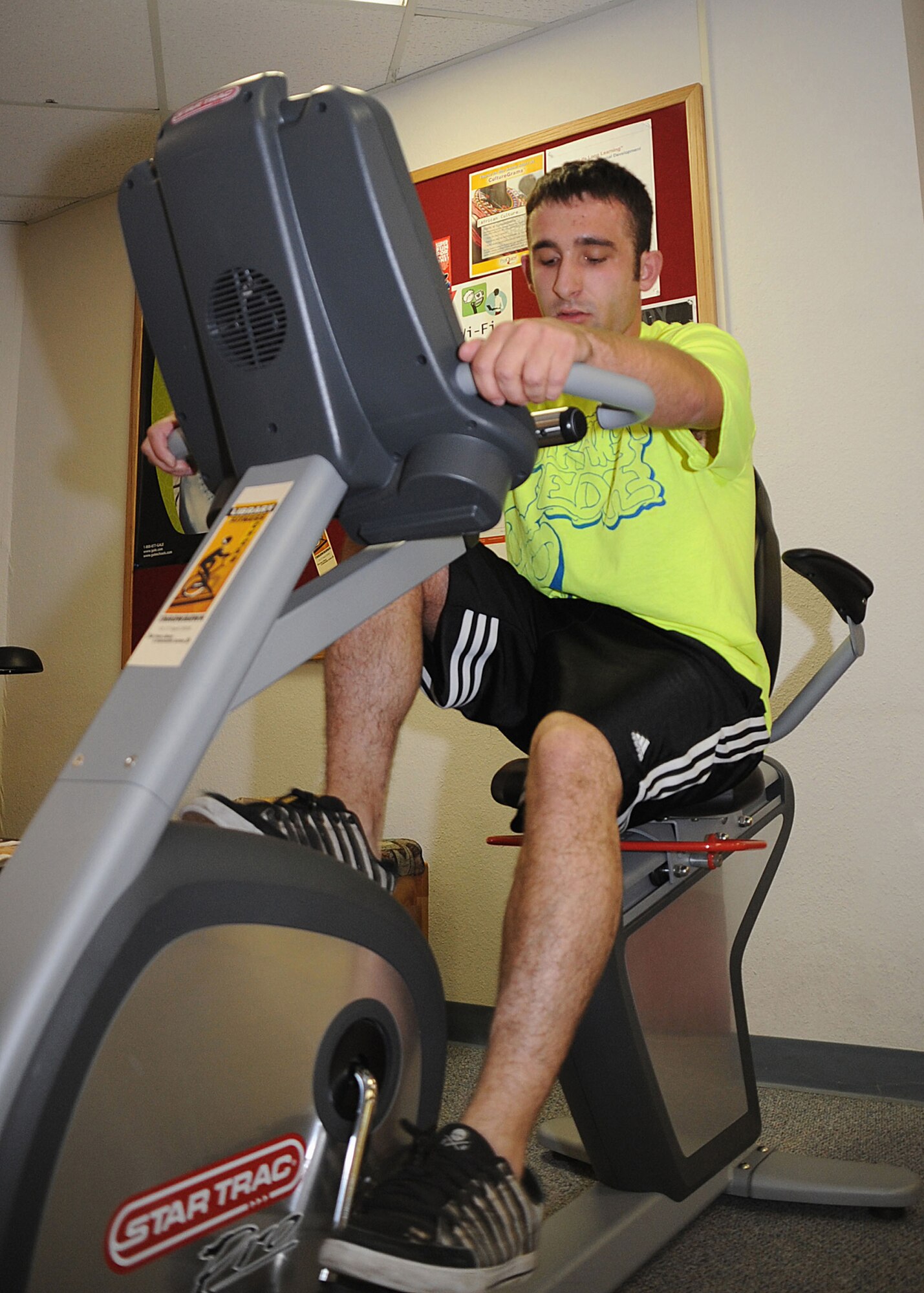CANNON AIR FORCE BASE, N.M.-- Airman 1st Class Christopher Fultz, 27th Special Operations Maintenance Group, begins his 20-mile goal on the stationary bicycle at the Cannon Library April 16. Cannon's library was one of 26 in the Air Force that vied for honors April 13-17 as the library that logged the most miles ridden and most pages read in a 60-hour period. Local readers rode 516.45 miles and read 1,595 pages during the period. (U.S. Air Force photo/Airman 1st Class Maynelinne De La Cruz)