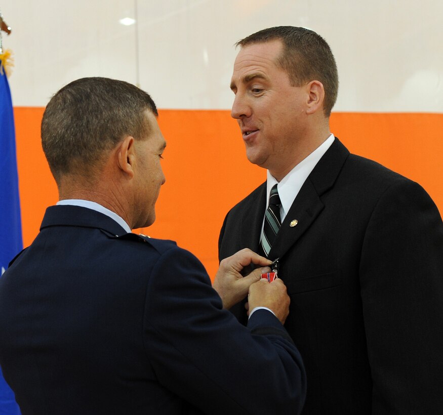 LANGLEY AIR FORCE BASE, Va. -- Retired Maj. Gregory Woosley, Air Combat Command Air and Space Operations Directorate, receives a Bronze Star from Brig. Gen. Mark A. Barrett, 1st Fighter Wing commander, during Hampton Roads Air Force Week's Honoring America's Veterans ceremony April 20. The Bronze Star Medal is a United States Armed Forces individual military decoration which is awarded for bravery, acts of merit, or meritorious service.  (U.S. Air Force photo/Airman 1st Class Zachary Wolf)