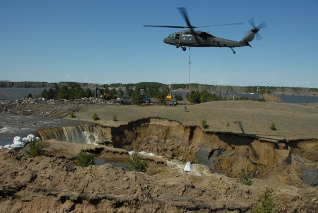 A North Dakota National Guard helicopter places 1-ton sandbags at the Cottonwood Creek Dam at Lake LaMoure on April 19, 2009.  The sandbags slowed the water flow from the eroded spillway.  Photo by SMSgt David Lipp, 119th Wing Public Affairs
