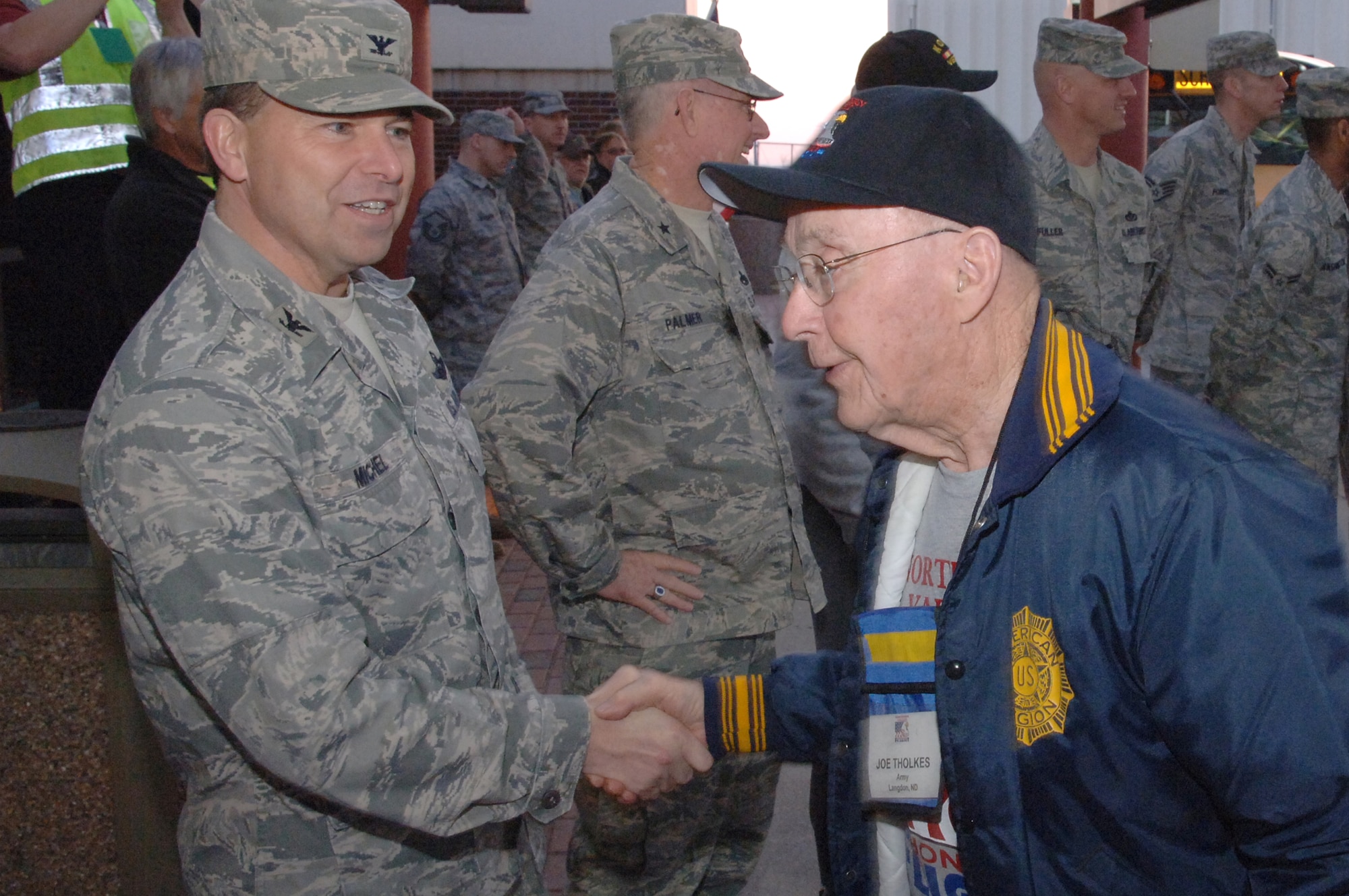 Col. John Michel (left), 319th Air Refueling Wing commander, shakes the hand of Joe Tholkes, a World War II veteran, as he enters the airport April 17. A group of about 90 veterans departed Grand Forks International Airport on board an Honor Flight trip to Washington, D.C. (U.S. Air Force photo/Master Sgt. Paul Cox)