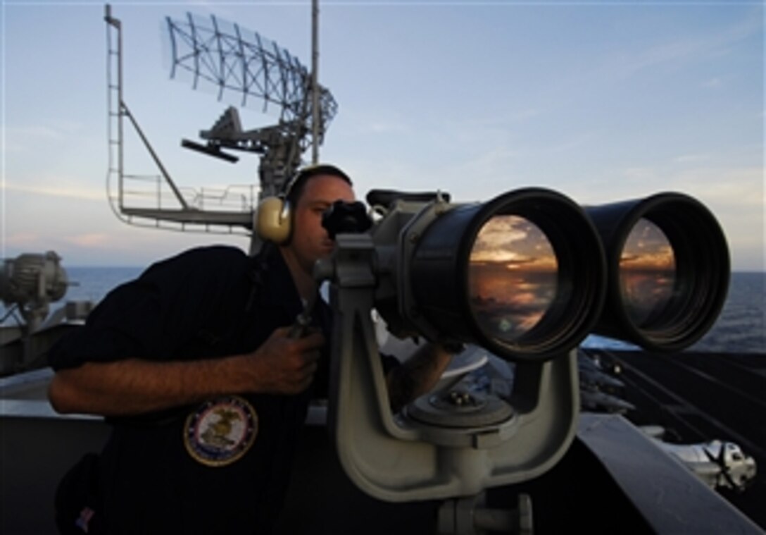 U.S. Navy Seaman Apprentice Paul Coombs uses the "big eyes" to locate surface contacts while standing port forward lookout watch on the island structure aboard the aircraft carrier USS John C. Stennis (CVN 74) underway in the Pacific Ocean on April 8, 2009.  The ship is on a six-month deployment in the western Pacific Ocean.  