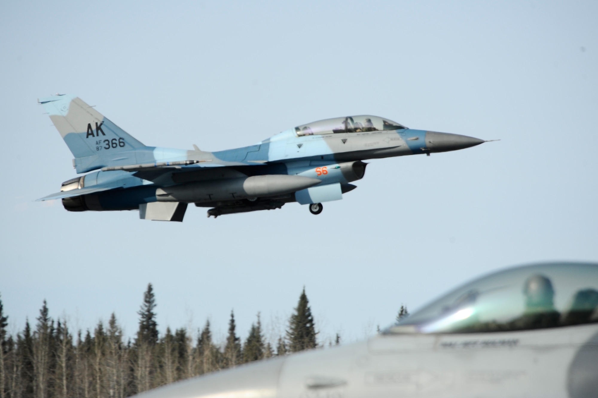 An F-16 Aggressor, 18th Aggressor Squadron, takes off while an F-16 Fighting Falcon, 35th Fighter Squadron, Kunsan Air Base, Korea, taxis towards the end of the runway during RED FLAG-Alaska 09-2 April 21, 2009, Eielson Air Force Base, Alaska. The Aggressors play a vital role as red forces during the exercise which helps blue forces sharpen their combat skills by flying ten simulated combat sorties in a realistic threat environment.  (U.S. Air Force Photo/Senior Airman Jonathan Snyder)