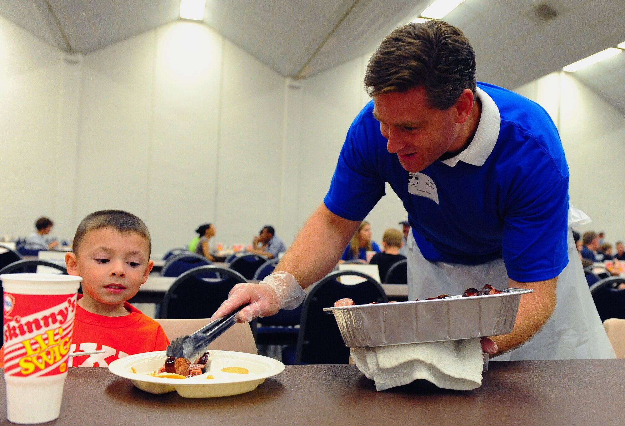 DYESS AIR FORCE BASE, Texas -- Tyson Estes, age 5, gets a second helping of sausage, during the World?s Largest Barbeque by Sam Sloane, a volunteer from Morgan Stanley and an honorary commander of the 77th Weapons Squadron here, April 18.  The World?s Largest Barbeque is sponsored by the Abilene Chamber of Commerce to show appreciation to active duty members, retired military and military dependents.  (U.S. Air Force photo by Staff Sgt. Connor Estes).  