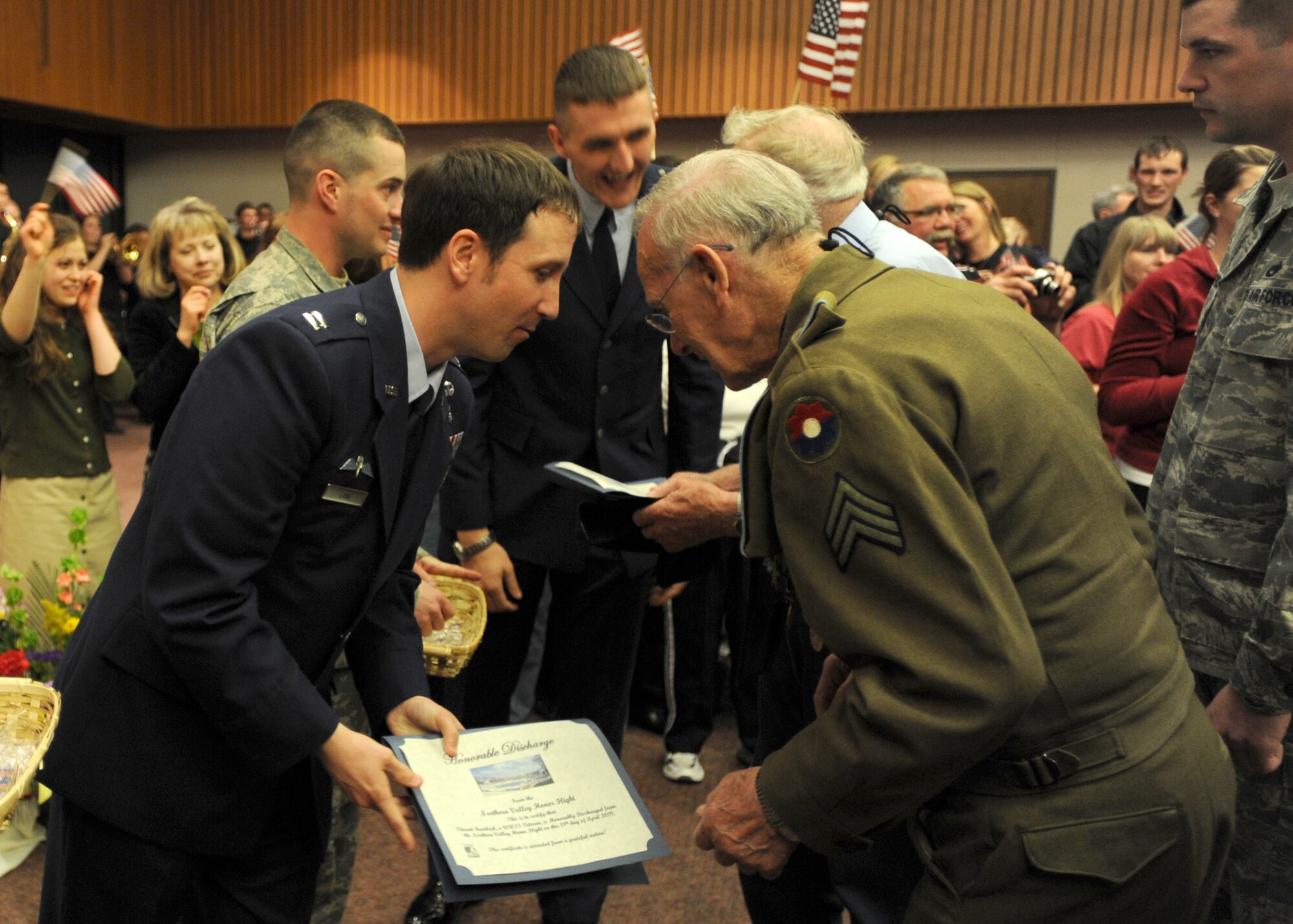 Capt. John Lane (left), 319th Medical Support Squadron, hands Army veteran Vance Rambeck his "Discharge Certificate" upon completion of the Northern Valley Honor Flight. More than 95 World War II veterans from the Red River Valley region of North Dakota and Minnesota participated in the flight. 