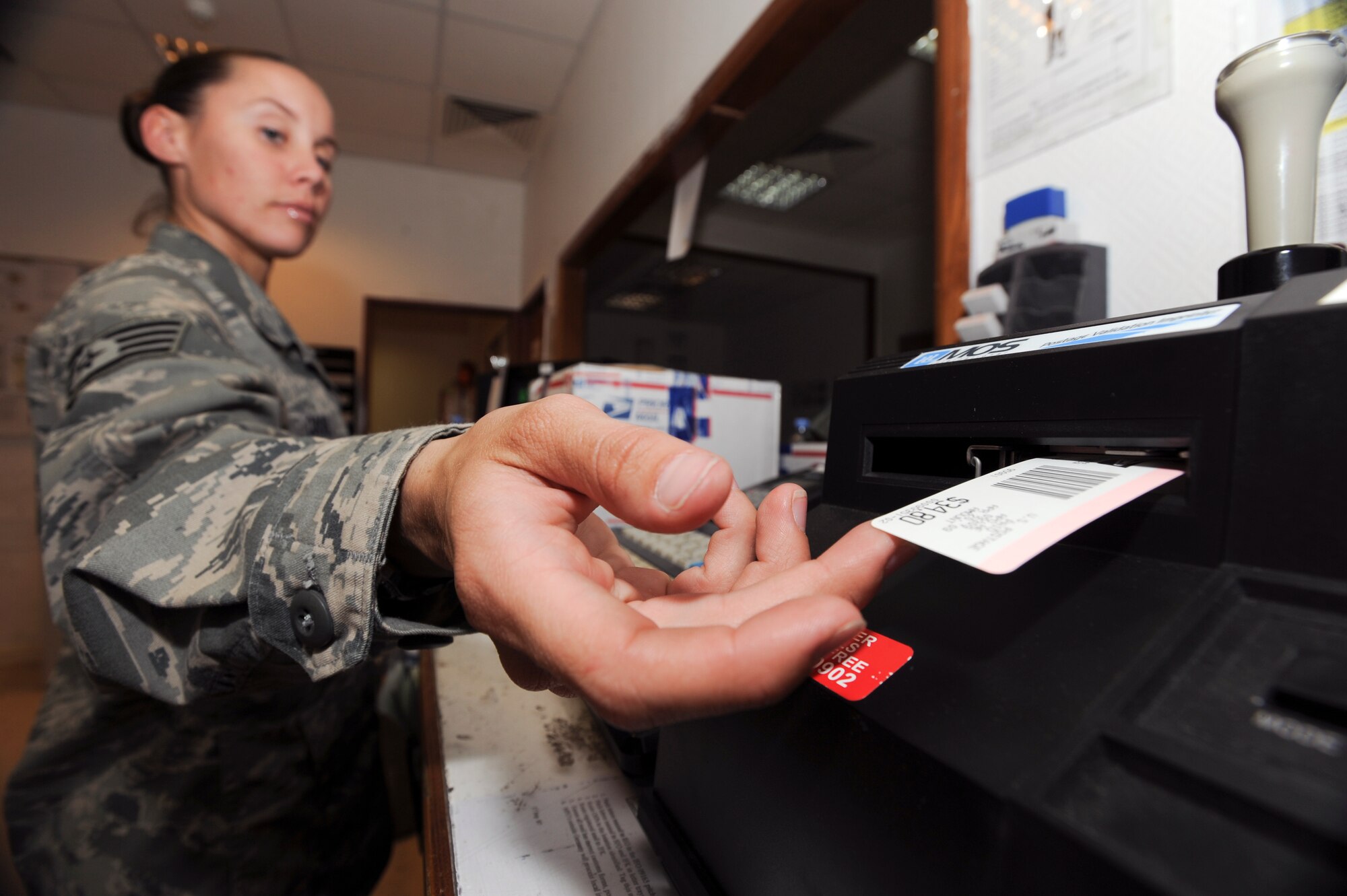 Staff Sgt. Cassandra Casul, a postal clerk with the 379th Expeditionary Communication Squadron, reaches for a price barcode after weighing a customer's package, April 20, 2009, in an undisclosed location in Southwest Asia.  Sergeant Casul and fellow postal clerks handle all outgoing mail for the base. Sergeant Casul is originally from Kissimmee, Fla. and is deployed from Wright-Patterson Air Force Base, Ohio in support of Operations Iraqi and Enduring Freedom, and Combined Joint Task Force - Horn of Africa.  (U.S. Air Force Photo by Staff Sgt. Joshua Garcia/released)