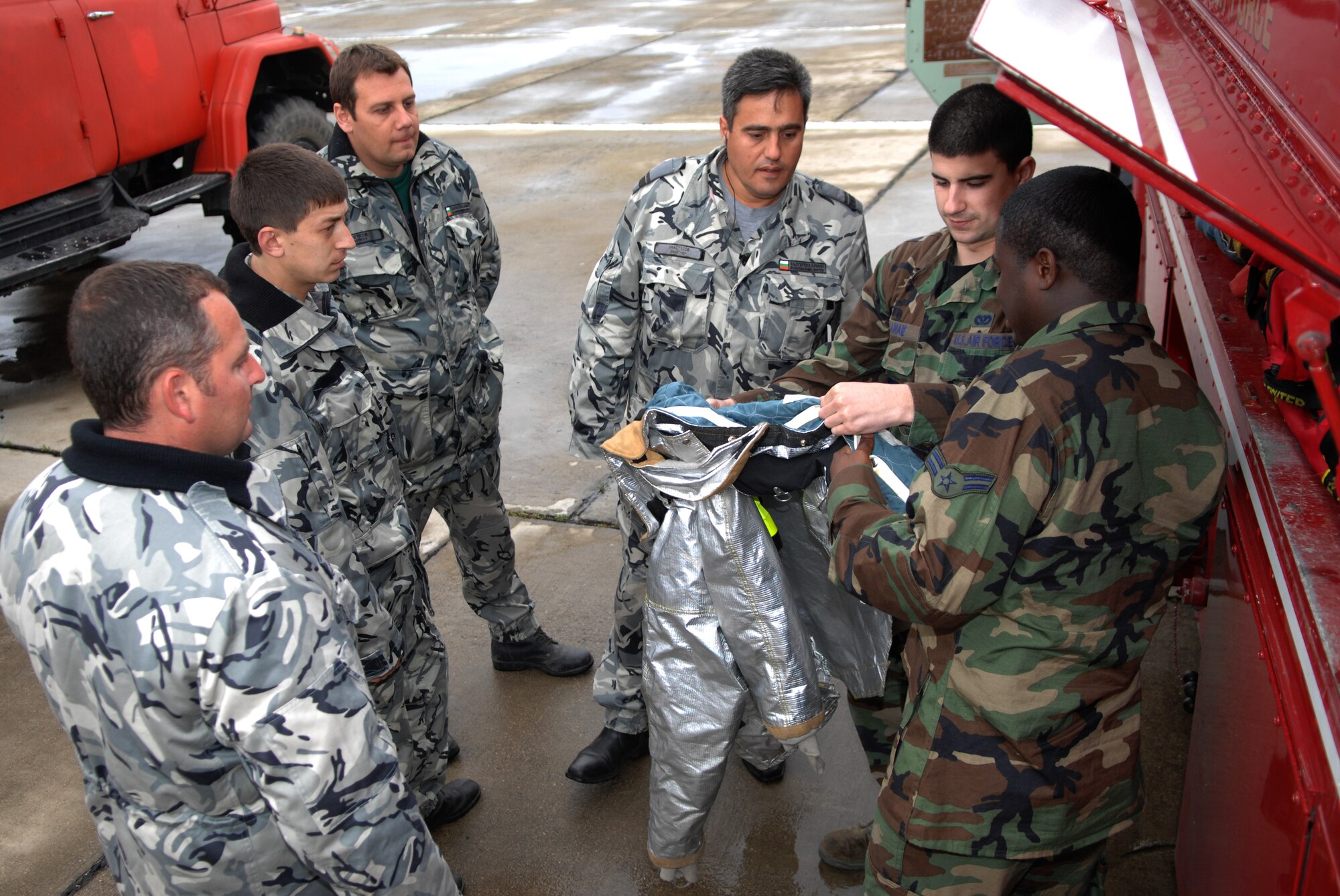 BEZMER AIR BASE, Bulgaria – Senior Airman Spencer K. Lahaie (left) and Airman 1st Class Arthur J. Lewis (right), 52nd Civil Engineer Squadron firefighters, demonstrate equipment and fire suits on board a P-19 fire truck to the Bulgarian firefighters.  A six-man fire department team deployed to Bezmer Air Base, Bulgaria, to support “Reunion April 2009,” a joint training exercise. (U.S. Air Force photo by Master Sgt. Bill Gomez) 