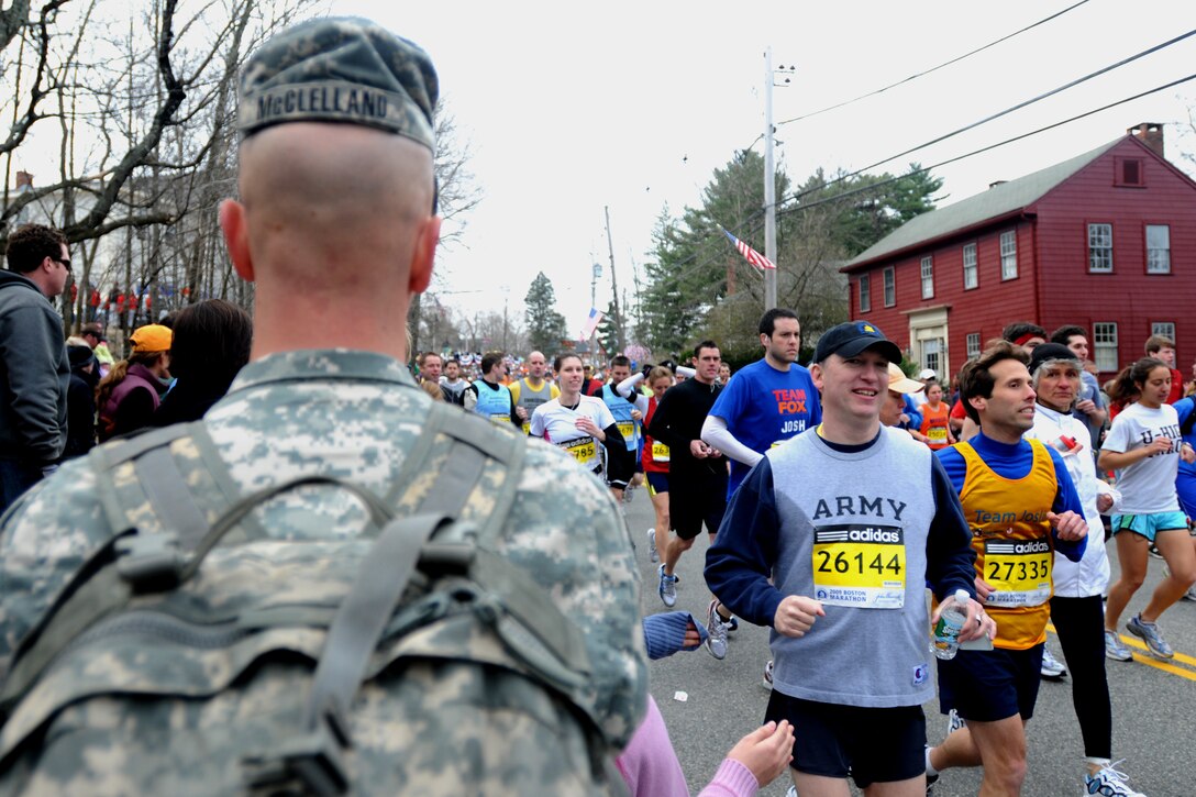 Army Chief Warrant Officer Thomas R. Lamont, a military personnel technician with Headquarters Company, 26th Maneuver Enhancement Brigade, wears an Army T-shirt as he runs past Army Sgt. Brian L. McClelland in Hopkinton, Mass., during the 113th running of the Boston Marathon, April 20, 2009. Lamont finished the marathon with a time of 4 hours, 47 minutes. U.S. Army photo by Sgt. James Lally 