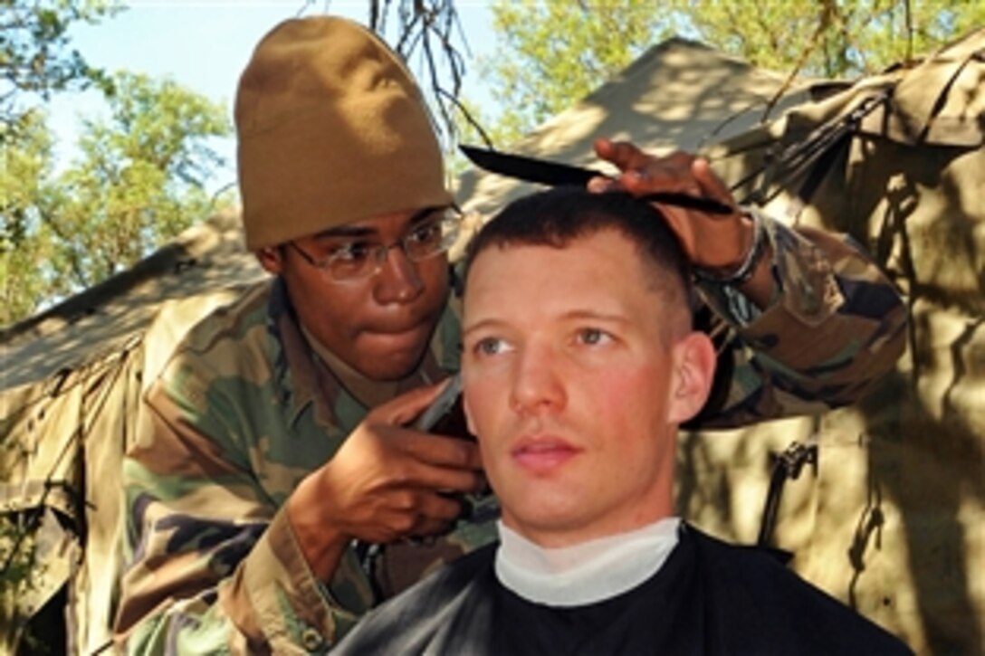 U.S. Navy Petty Officer 3rd Class Cedric Obryant, left, gives a haircut to Lt. Aaron Ripple in the field during Operation Bearing Duel on Fort Hunter Ligget, Calif., April 20, 2009. Obryant is assigned to Naval Mobile Construction Battalion. Operation Bearing Duel is an annual field exercise to test a battalion's ability to deploy to a contingency environment.