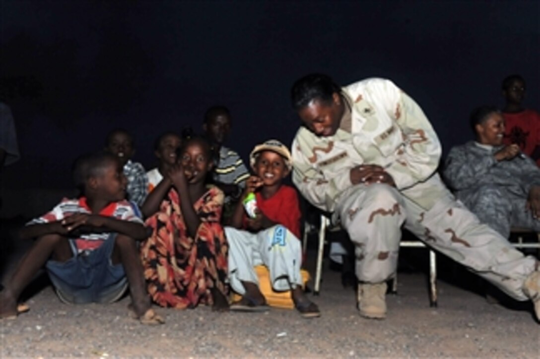 U.S. Navy Petty Officer 2nd Class Donna Powers-Brown, a volunteer attached to the Combined Joint Task Force-Horn of Africa, sits with local children during the weekly movie night event at Ecole Douda Primary School in Djibouti on April 16, 2009.  Service members from the 414th and 489th civil affairs companies, assigned to the Combined Joint Task Force-Horn of Africa, are hosting the event.  Service members volunteer to interact regularly with locals to establish relationships in the community.  