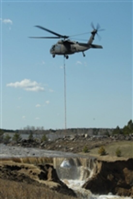 A UH-60 Black Hawk helicopter from the 1-112th Aviation Battalion, North Dakota National Guard, Bismarck, N.D., prepares to drop a 1-ton sandbag in the washed out portion of the emergency spillway of the Cottonwood Springs Dam, also called Lake LaMoure, near LaMoure, N.D., on April 19, 2009.  The spillway is eroding and releasing more water than it was designed to release.  National Guard helicopters are being used to lessen the damage to the spillway.  The sandbags are being used to create a tier system so the water slows down and forms into different pools below the waterfall.  