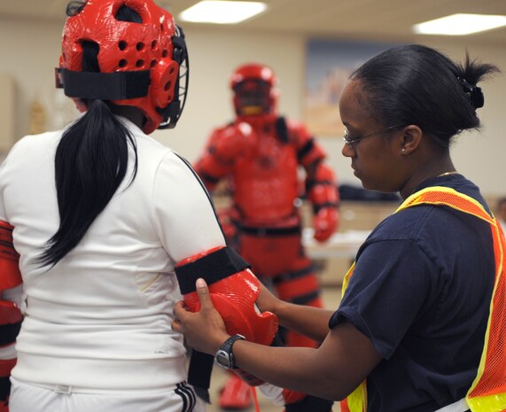 Staff Sgt. Ashley Glasgow,  a security forces officer with the 99th Security Forces Squadron, adjusts a student's personal protective gear, April 17, Nellis Air Force Base, Nev. University of Las Vegas (UNLV) Police, Sexual Assault Response Coordinators  (SARC) and security forces personnel team up to provide Nellis Airmen the Rape Aggression Defense (RAD) Class. (U.S. Air Force photo by/Senior Airman Nadine Y. Barclay/RELEASED)