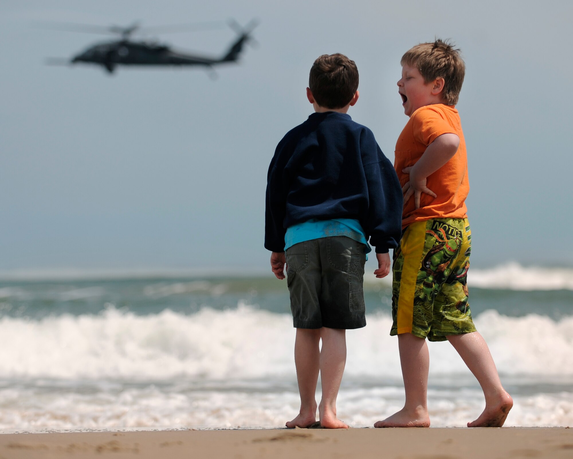 LANGLEY AIR FORCE BASE, Va. -- Tyler Simons and Michael Harris watch as an HH-60G Pave Hawk helicopter from Moody Air Force Base, Ga. hovers over the water during the Joint Air Power Demonstration at the Virginia Beach boardwalk April 22.  The demonstration highlighted the role of joint military operations.  This is one of the many events occurring in the Hampton Roads area as the Air Force members say "thank you" to the community during Hampton Roads Air Force Week.  (U.S. Air Force photo/Senior Airman Vernon Young) 