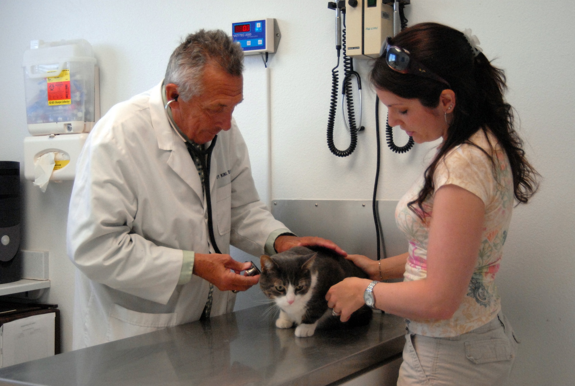Dr. Harry King, base veterinarian, gives a cat a check-up, as the owner, Rendi Gause keeps the cat still  April 22 at the veterinarian clinic. The veterinarian offers vaccines, micro chipping and check-ups for base personnel's cats and dogs. Dr. King has been hired to fill the man-power shortage the vet clinic was experiencing. (U.S. Air Force photo/2nd Lt. Belena Marquez)