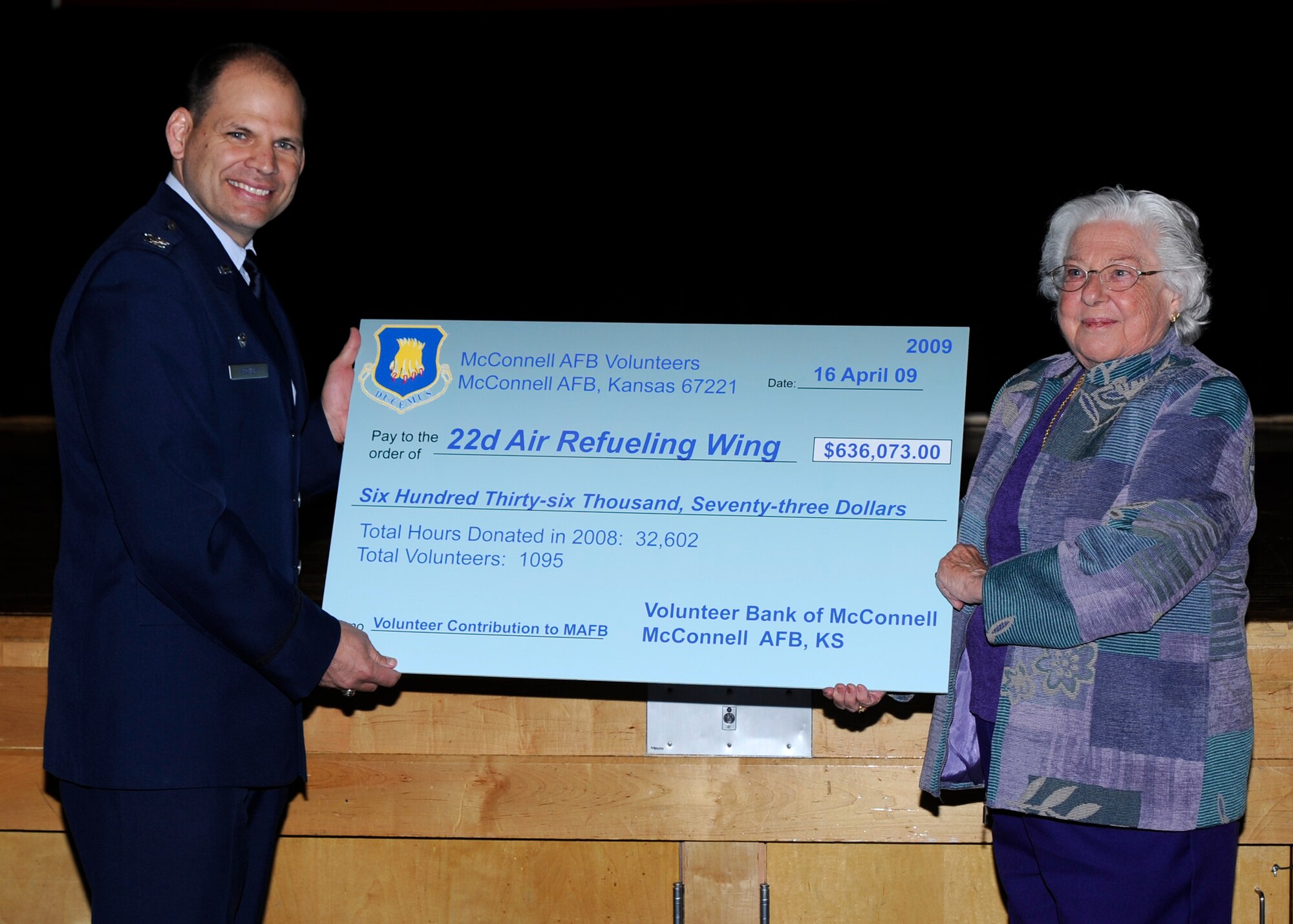 MCCONNELL AIR FORCE BASE, Kan. -- Millie Suer, America Red Cross volunteer, presents Col. James C. Vechery, 22nd Air Refueling Wing commander, with a check for $636,073 during the 18th annual Volunteer Appreciation Ceremony in the Robert J. Dole Community Center ballroom, April 16. The amount on the check represented the amount of money saved through the use of more than 1,095 McConnell volunteers. (Photo by Airman Justin Shelton)