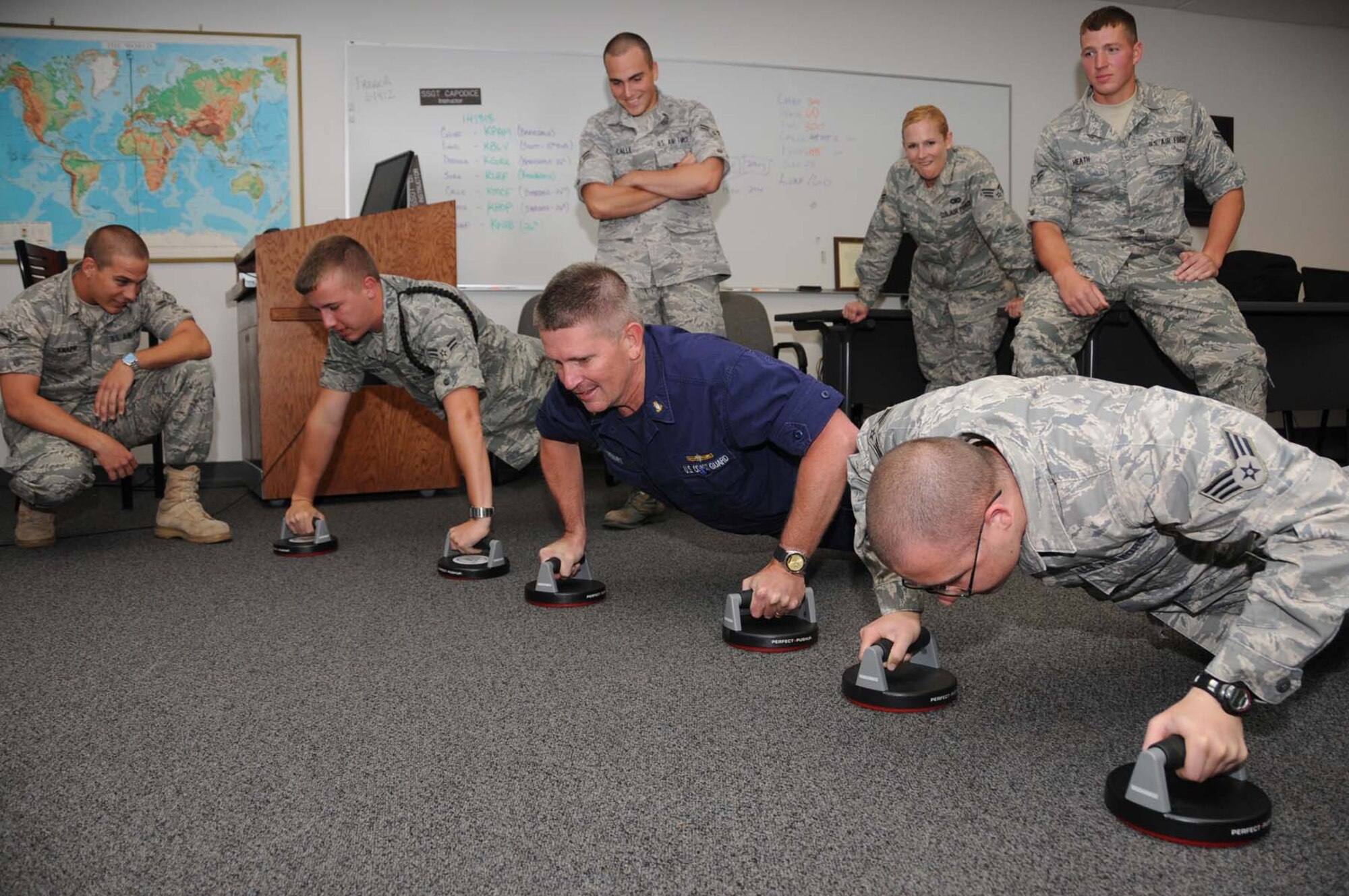 Front from left, Airman Knapp encourages Airman Sura, Chief Stewart, and Airman Dobyna as they do pushups.  Back from left, Airmen Calle, Lund and Heath await their turns.  (U.S. Air Force photo by Kemberly Groue)