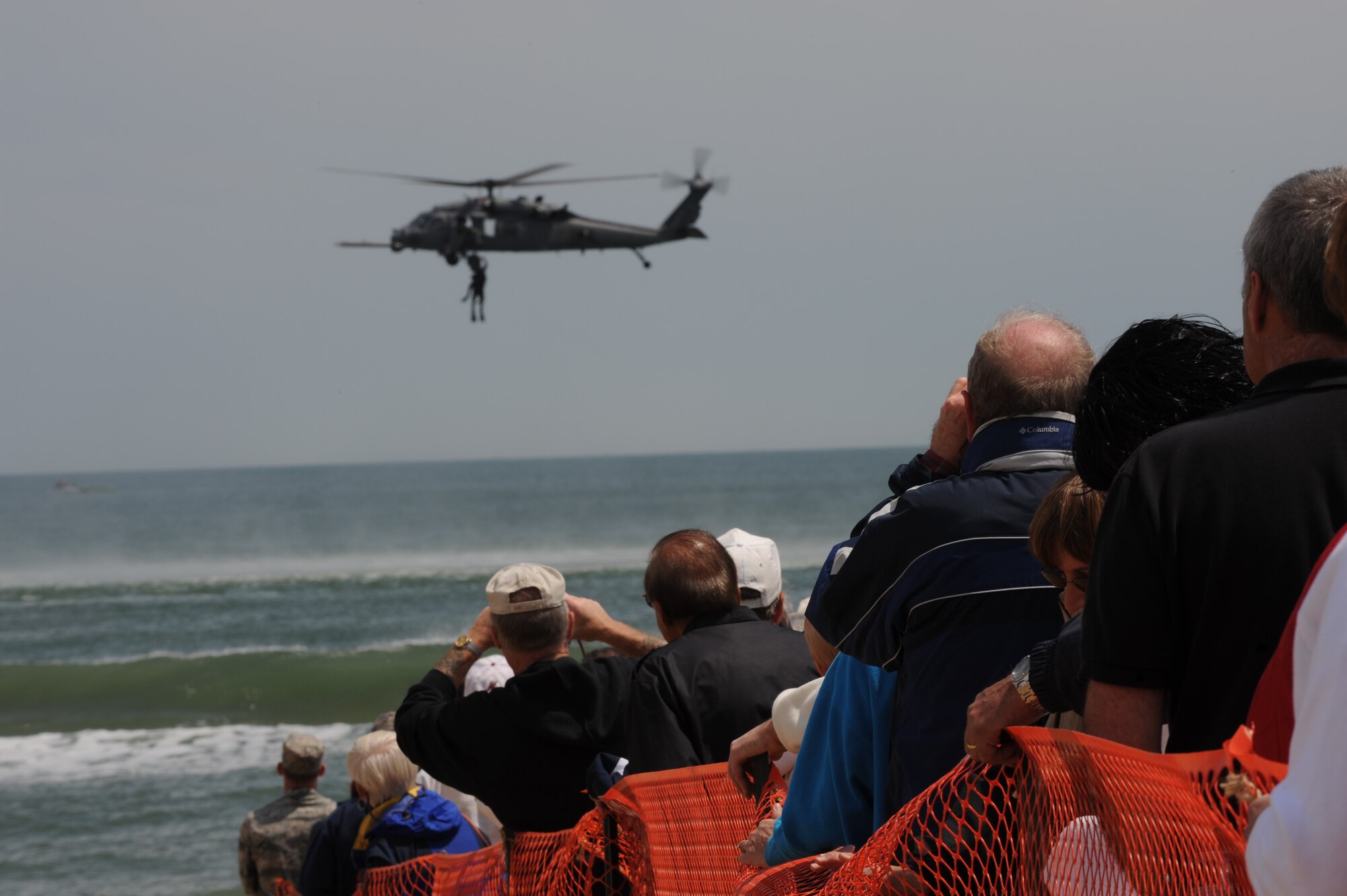 LANGLEY AIR FORCE BASE, Va. -- Spectators photograph the 38th Rescue Squadron pararescuemen, as they are pulled up to the 41st Rescue Squadron HH-60G Pave Hawk helicopter, during the Joint Air Power Demonstration at Virginia Beach boardwalk April 22.  The  demonstration showcased the critical role air power plays in the joint fight. The 38th and 41st Rescue Squadrons are at Moody Air Force Base, Ga. (U.S. Air Force Photo/Senior Airman Ashley Hawkins)
