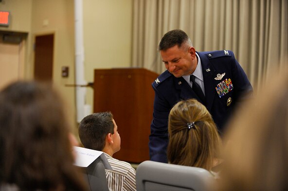 Col. Edward McKinzie, commander of the 505th Command and Control Wing at Hurlburt Field, presents his first Commander's Coin to his son, Connor, during the change of command ceremony here April 17. Maj. Gen. Stephen Hoog, commander of the U.S. Air Force Warfare Center at Nellis Air Force Base, officiated at the ceremony.