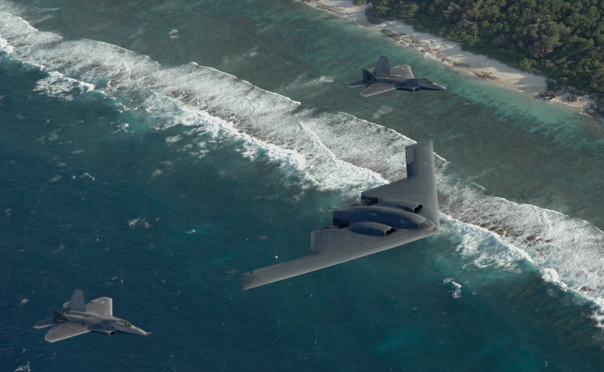 Two F-22 Raptors and a B-2 Spirit bomber deployed to Andersen Air Force Base, Guam, fly in formation over the Pacific Ocean.  The deployment to Andersen marks the first time F-22s and B-2s, the key national strategic stealth assets in the Air Force inventory, deployed together outside the continental United States. (U.S Air Force photo/Master Sgt. Kevin J. Gruenwald)
