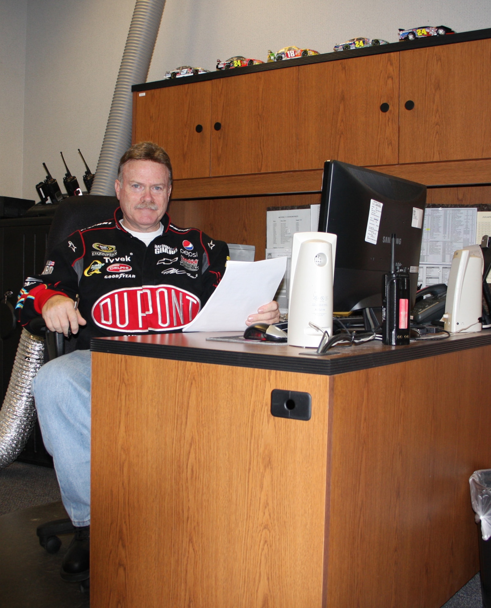 WRIGHT-PATTERSON AIR FORCE BASE, Ohio - Master Sgt. Steve Dunn, 445th Maintenance Operations Flight, shows off his NASCAR jacket at work.  Sergeant Dunn became addicted to NASCAR after watching his first race earlier this year. Some of the models he bought are shown here on top of his desk (Air Force photo/Stacy Vaughn).