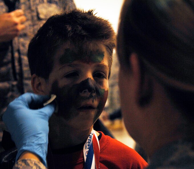 WHITEMAN AIR FORCE BASE, Mo. - A young "Airman" has his face painted with camouflage April 18 during Operation Spirit. Operation Spirit is a simulated deployment line for school-aged kids that allows children to experience what their military parents go through during a deployment. The "Airmen" were accompanied by their parents and received goodies form several base agencies. (U.S. Air Force photo/Staff Sgt. Jason Barebo)