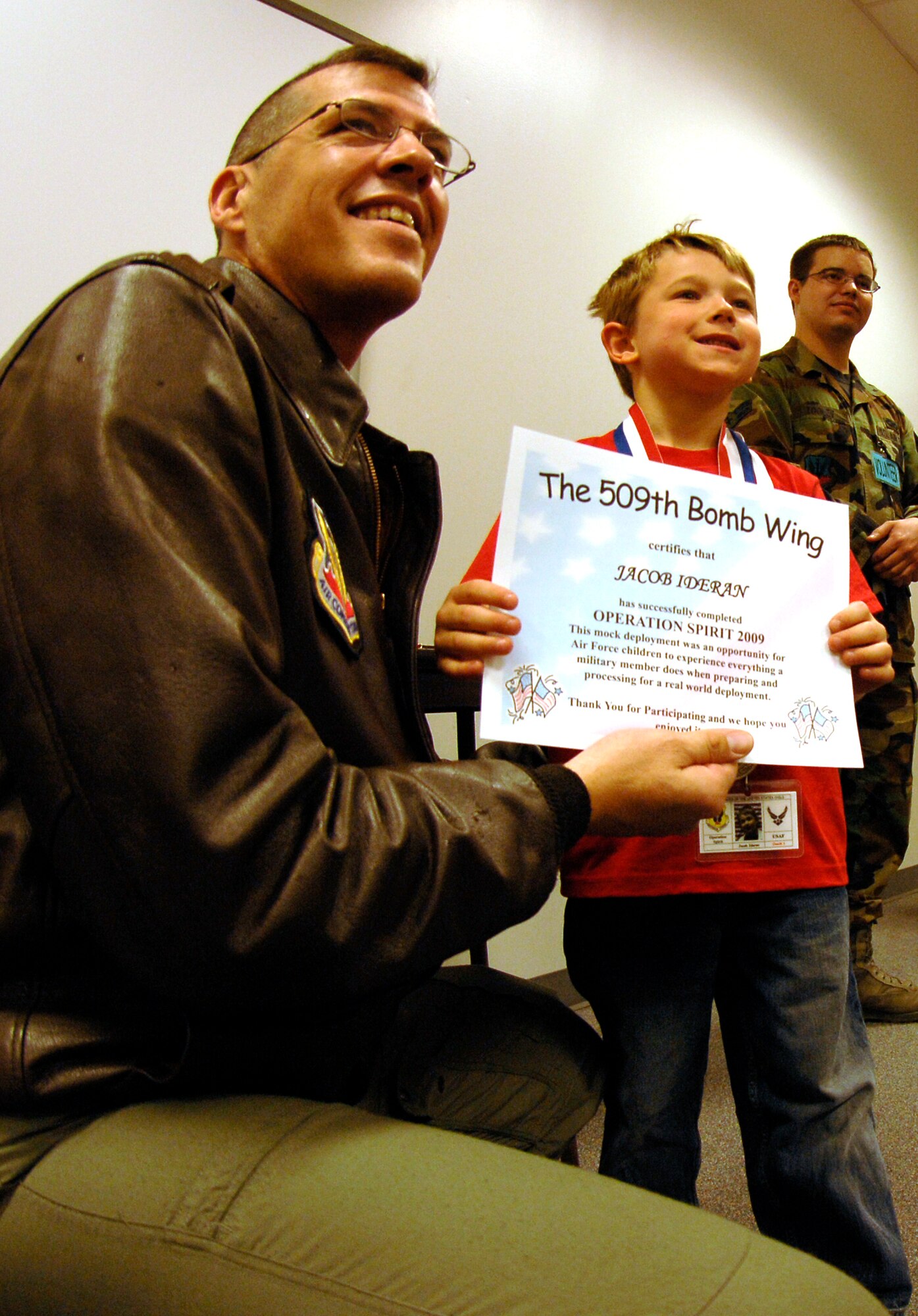 WHITEMAN AIR FORCE BASE, Mo. - Col.  Thomas Bussiere, 509th Operations Group commander, presents "Airman" Jacob Ideran with a certificate of completion April 18 during Operation Spirit. The certificate reads "This mock deployment was an opportunity for Air Force children to experience everything a military member does when preparing and processing for a real-world deployment.(U.S. Air Force photo/Staff Sgt. Jason Barebo)