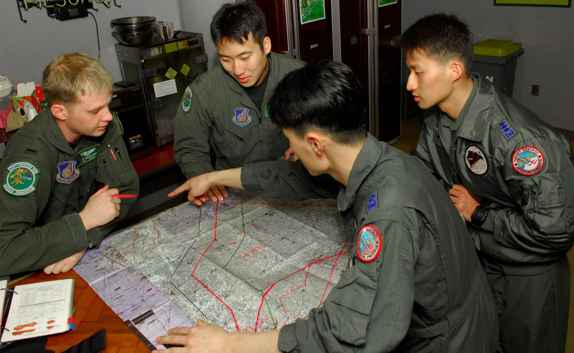 First Lts. Mike McCarthy and Al Chang from the 25th Fighter Squadron at Osan Air Base, South Korea, discuss their flight plans as they prepare for an upcoming mission with Capt. Pak Chan-mu and Maj. Chong Hyaon-dong from the 15th Composite Wing at Seoul Air Base. The 51st Fighter Wing hosted a combined exchange exercise called the Buddy Wing Program this week, with the participation from the  25 FS here and the South Korean 15th CW. The aircrew members trained together allowing both units to introduce tactics and improve interoperability between the two countries. (U.S. Air Force photo/Senior Airman Stephenie Wade)