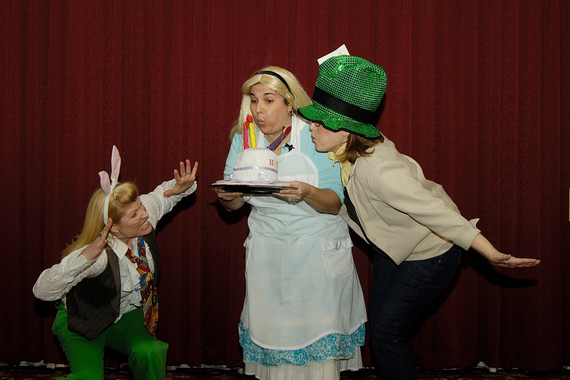 Alice (Larissa Cattles, center) blows out the candles on her ‘unbirthday’ cake at the Hanscom Spouses Club’s Mad Hatter Tea Party, with help from the March Hare (Karen Jenkins, left) and the Mad Hatter (Cynthia Nunes-Taijeron). The tea party was held April 17, at the Minuteman Club.  (Air Force photo by Linda LaBonte-Britt)
