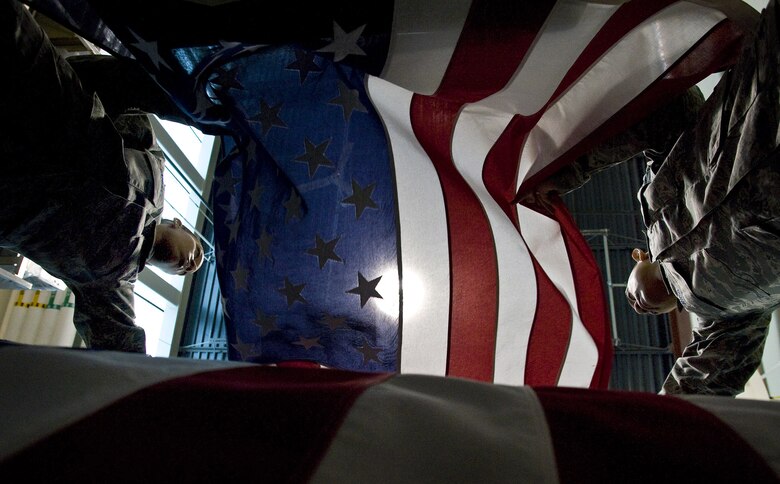 Shipping specialists Staff Sgt. Star Samuels, left, and Tech. Sgt. Willard Rico place a U.S. flag over a casket while practicing  procedures for the dignified transfer of remains shipping process at the Charles C. Carson Center for Mortuary Affairs, Dover Air force Base, Del., March 31, 2009. Both Airmen are on temporary duty at the center. Sergeant Samuels is from the 43rd Force Support Squadron, Pope AFB, N.C., and Sergeant Rico is from the 60th FSS, Travis AFB, Calif. (U.S. Air Force photo/Staff Sgt. Bennie J. Davis III)