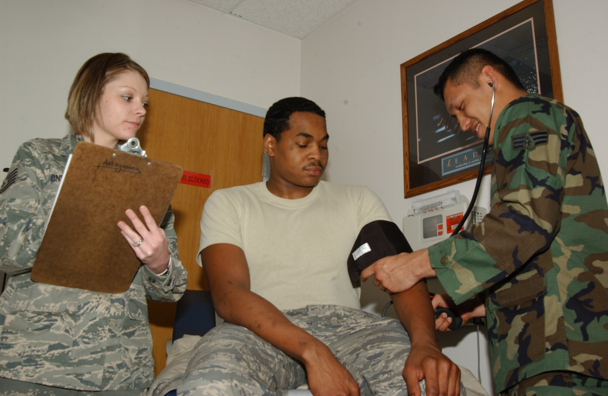 SCOTT AIR FORCE BASE, Ill. --Senior Airman Robert “Bob” Ancheta, Scott Family Health Clinic medical technician, checks the vitals of exercise patient, Airman 1st Class Mark Hunter, Public Health technician, while Tech. Sgt. Hilary Onesko, Public Health technician, evaluates the simulation. Airman Hunter went to the Clinic with symptoms of a food borne illness and the Clinic properly detected what was wrong with Airman Hunter. (U.S. Air Force photo/Airman 1st Class Amber Kelly-Woodward) 