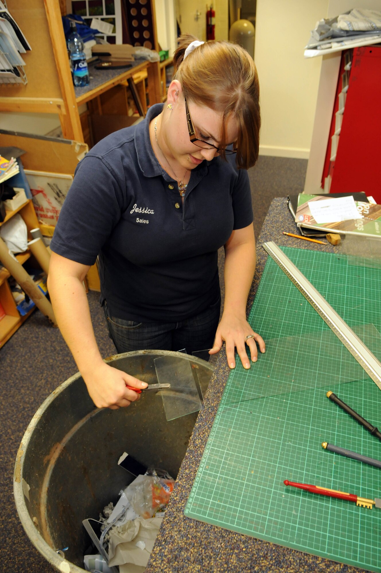 Jessica Littledale, 100th Force Support Squadron sales clerk, practices cutting glass at the RAF Mildenhall frame shop.  Glass, while relatively simple to cut, requires a steady hand and a gentle touch to ensure perfection, something the staff at the frame shop strives for with every product they create.  (U.S. Air Force photo by Staff Sgt. Austin M. May)