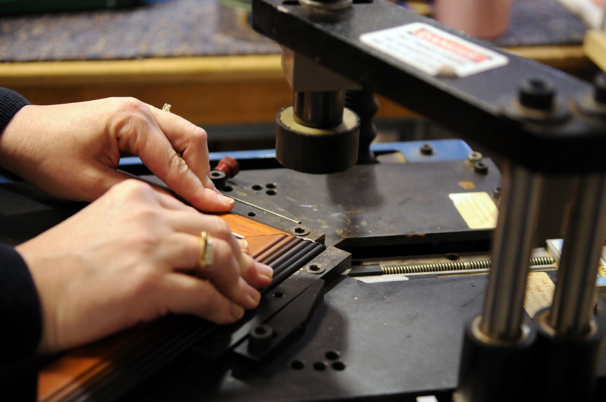 Chris Acker, 100th Force Support Squadron professional framer, uses a pneumatic press to join segments of a wooden frame together at the RAF Mildenhall frame shop.  The frame shop employs a variety of equipment and machines to produce high-quality frames that with display their contents with prestige for years.  (U.S. Air Force photo by Staff Sgt. Austin M. May)