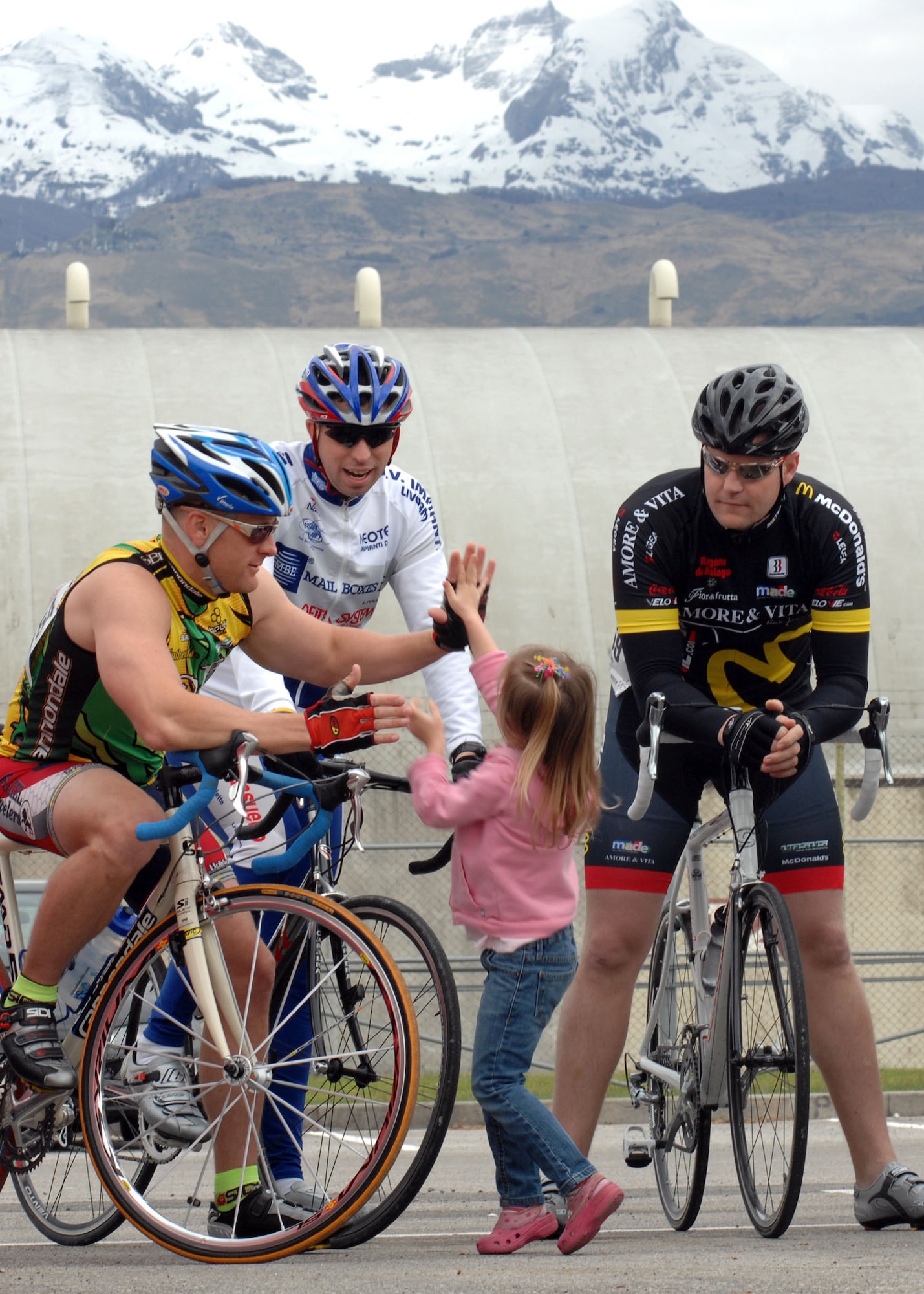 Timothy Schreiner, 31st Maintenance Squadron, receives a high-five from his five-year-old daughter Brynn while talking with fellow maintainers Aron Tidwell, center, and Erik Ryland, right, prior to the start of the 53 kilometer race here April 19. The race is part of the 2009 U.S. Forces Europe Road Cycling Series. (U.S. Air Force photo/Tech. Sgt. Michael O'Connor)