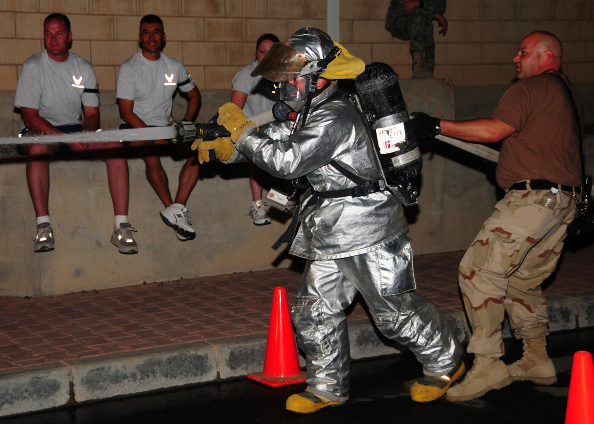 SOUTHWEST ASIA -- Airman 1st Class Paul Cange, 386th Expeditionary Civil Engineer Squadron firefighter, aims the charged fire hose downrange to knock down a cone to stop his time during the Firefighter Challenge, April 19. The competition was open to all personnel, however the participating firefighters were required to complete the course in full gear to include a full oxygen cylinder. Airman Cange is currently deployed from Francis S. Gabreski Air National Guard Base, N.Y., and is originally from Rocky Point, N.Y. (U.S. Air Force photo/ Senior Airman Courtney Richardson)