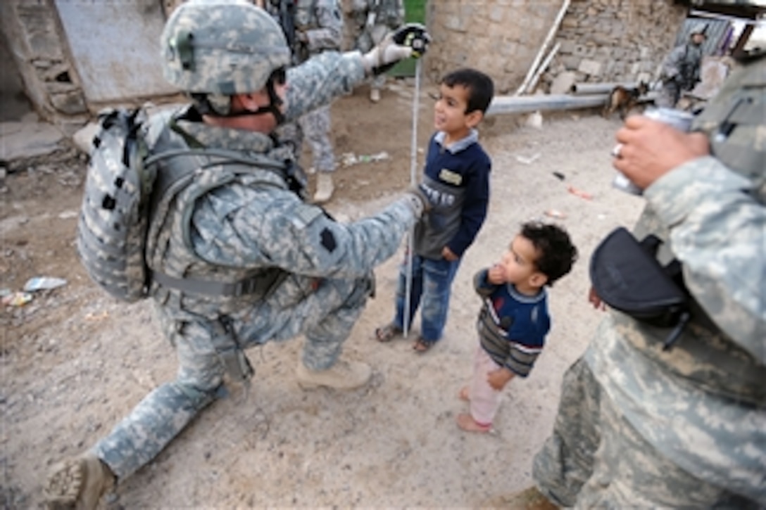 A U.S. Army soldier takes a moment to use an Iraqi child's tape measure to see how tall he is during a joint cordon and knock mission with Iraqi Security Forces in the village of Abu Atham, Iraq, on April 18, 2009.  The soldier is assigned to Charlie Troop, 2nd Squadron, 104th Cavalry Regiment, 56th Stryker Brigade Combat Team, 28th Infantry Division, Multi-National Division-Baghdad.  