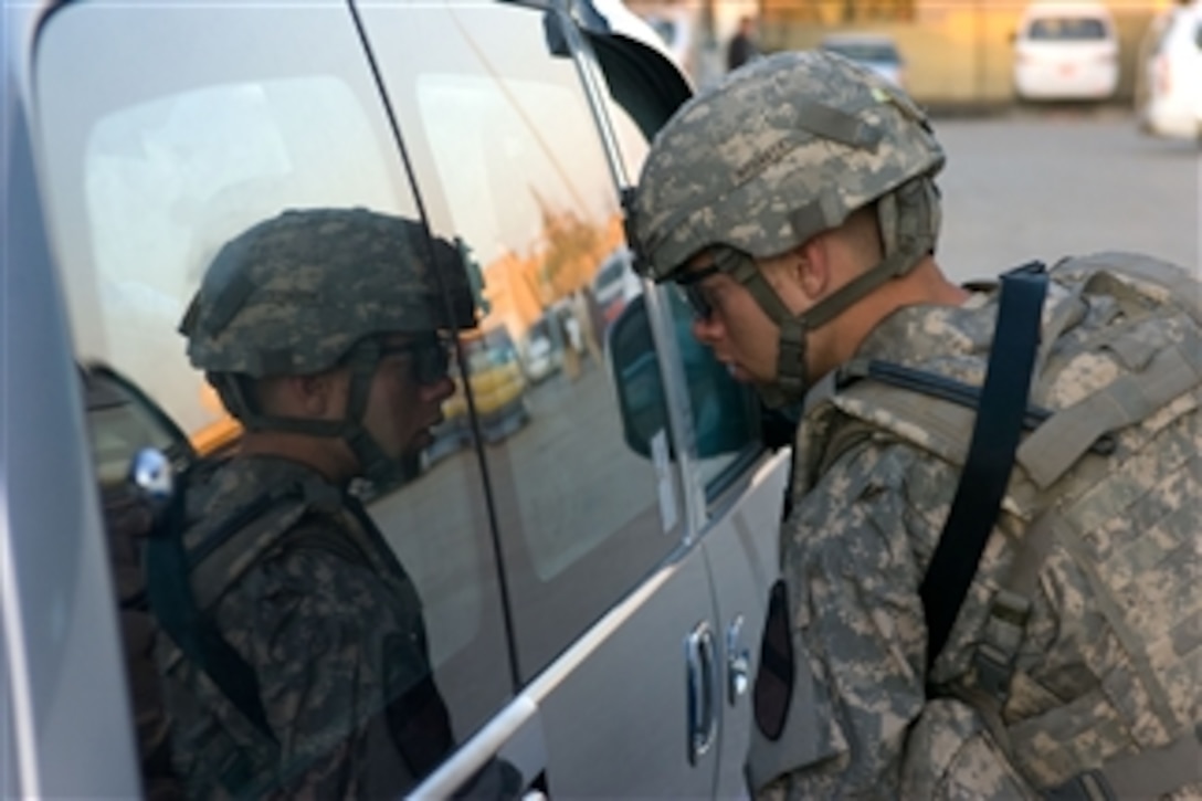 U.S. Army Sgt. David Crebo attached to 3rd Battalion, 82nd Field Artillery Regiment, 2nd Brigade Combat Team, 1st Cavalry Division, inspects the inside of a mini-bus during a cordon and search operation in the Douria district bus station in Kirkuk, Iraq, on April 14, 2009.  