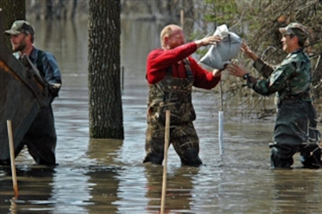 U.S. Air Force Master Sgt. Eric Johnson receives a sandbag from a civilian and passes it along a human chain of flood fighters standing in knee-high water southeast of Kindred, N.D., April 21, 2009. Johnson is assigned to the 119th Wing, North Dakota Air National Guard, and is helping the group build a temporary flood levee to hold back rising water from the Sheyenne River near a farmhouse.