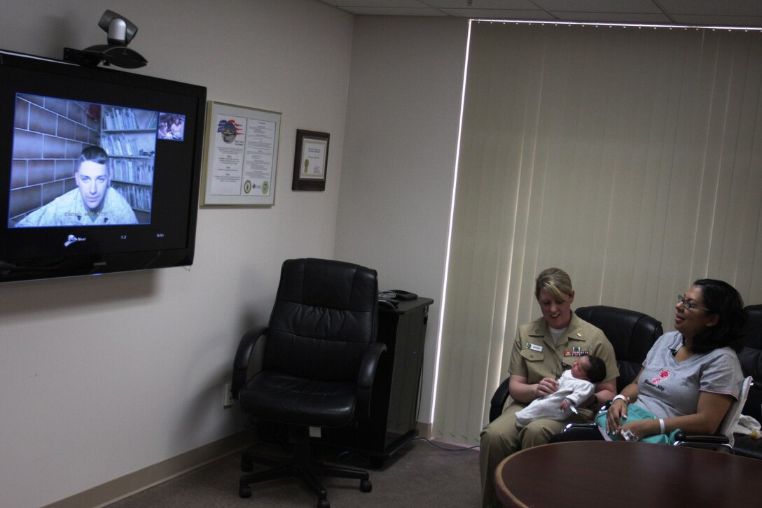 Kimberly Henry and Lt. Colleen Mahon, a maternal infant nurse at the Robert E. Bush Naval Hospital, introduce Sgt. John Henry, a squad leader with Company C, 1st Battalion, 7th Marine Regiment, to his newborn daughter Kelsi for the first time via Freedom Calls Foundation teleconference at the hospital April 23. Henry and the rest of 1/7 are currently deployed to Camp Baharia, Iraq.