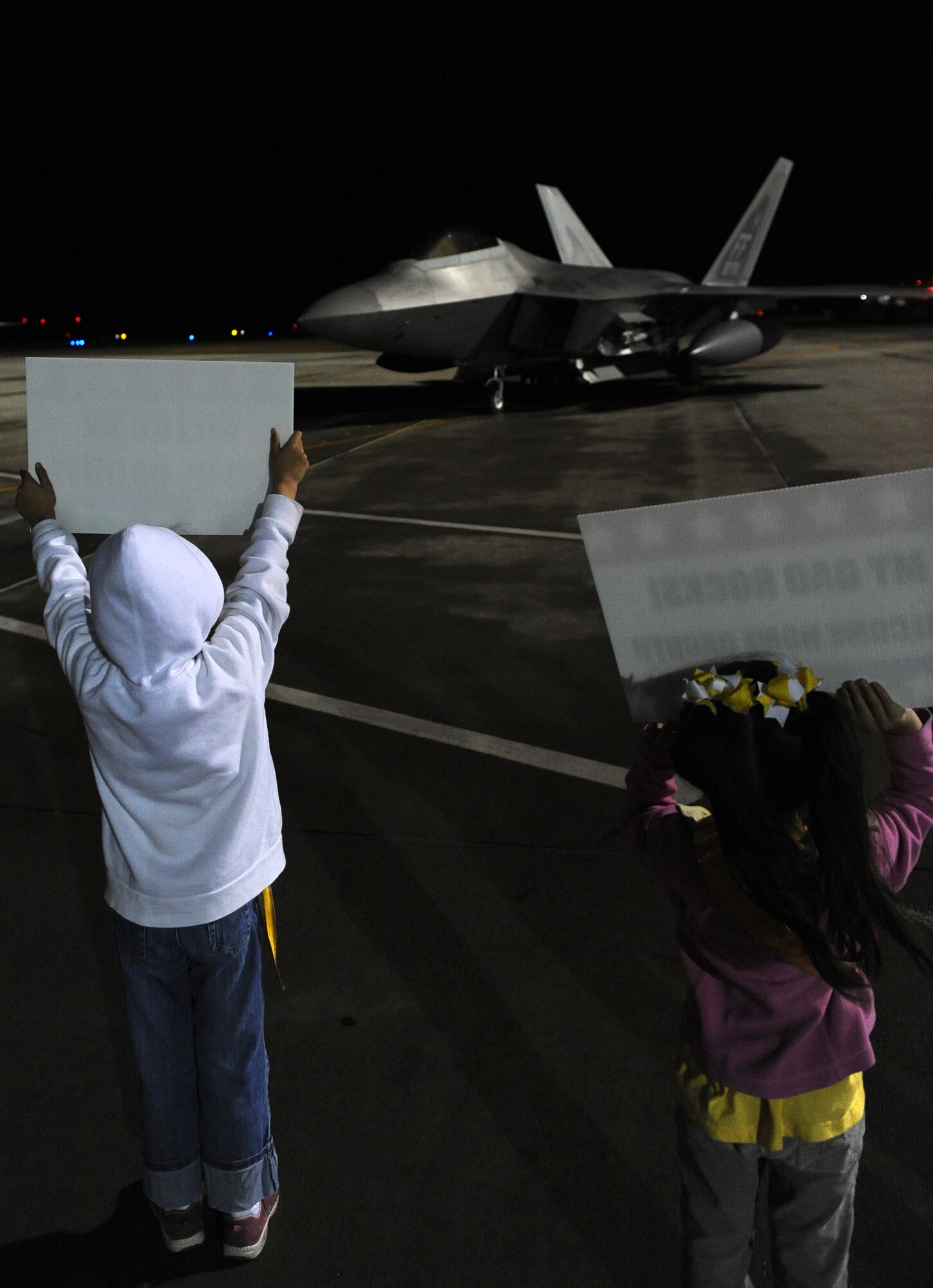 LANGELY AIR FORCE BASE, Va. -- Samantha and Julie Pilch, daughters of Lt. Col. Lance Pilch, 27th Fighter Squadron commander, welcome him home April 21. Colonel Pilch returned after leading a 120-day deployment to Kadena Air Base, Japan. “The 27th FS deployment to Kadena AB, Japan was a tremendous success,” said Colonel Pilch. “It is important to demonstrate the expeditionary capability of any aircraft including the F-22.” (U.S. Air Force photo/Airman 1st Class Zachary Wolf)