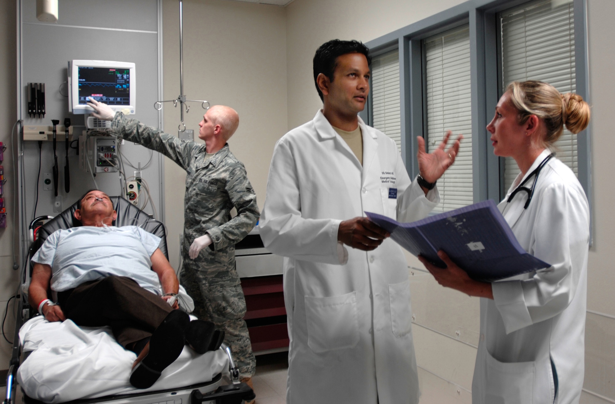 Emergency physicians Majs. (Drs.) Annette Williams (right) and Vikhyat Bebarta discuss patient care April 16 in the emergency department of Wilford Hall Medical Center at Lackland Air Force Base, Texas, while Airman 1st Class Casey Meed, a medical technician, prepares to take a patient's vitals. The three medics are assigned to the 59th Emergency Medical Squadron. Wilford Hall's emergency department is the only level-1 trauma emergency department in the Air Force and provides trauma care to local military and communities and accepts trauma referrals from a 22-county region of Southwest Texas. (U.S. Air Force photo/Master Sgt. Kimberly A. Yearyean-Siers) 