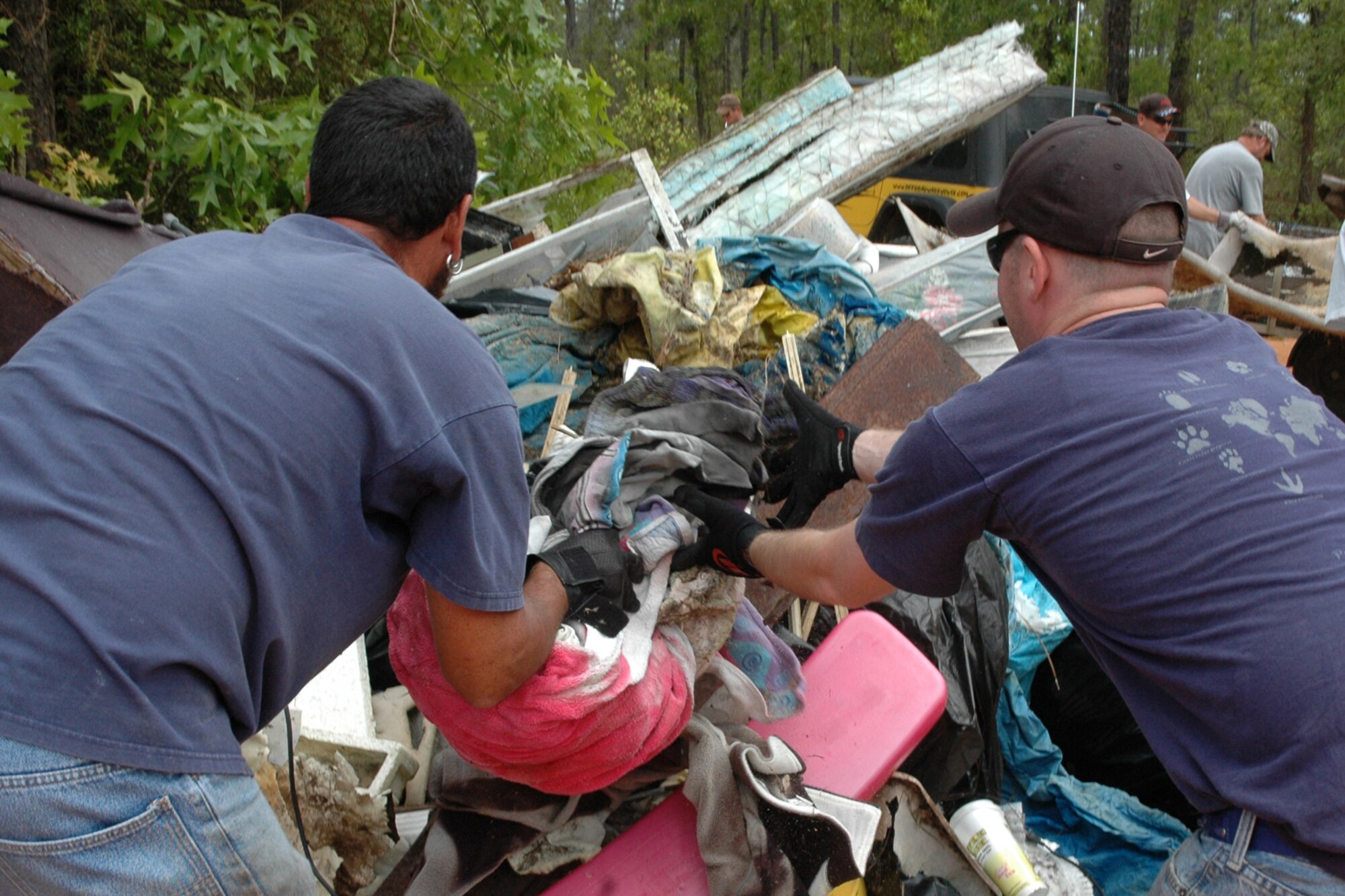 EGLIN AIR FORCE BASE, Fla. -- Tim Bryant and Coast Guard Lt. j.g. Mark Bruno pile trash they removed from the Eglin Reservation during the Eglin Earth Day clean up April 18 in honor of Earth Week. More than four tons of trash was found at the cite including mattresses, dish washers, recliners, ply wood, roof shingles, privacy fence, carpet, tires, refrigerators and microwaves, just to name a few. The piles of trash were removed the next day. Most of the volunteers for this project are members of local off-road and four-wheel drive clubs.  (U.S. Air Force photo/ Airman Anthony Jennings)