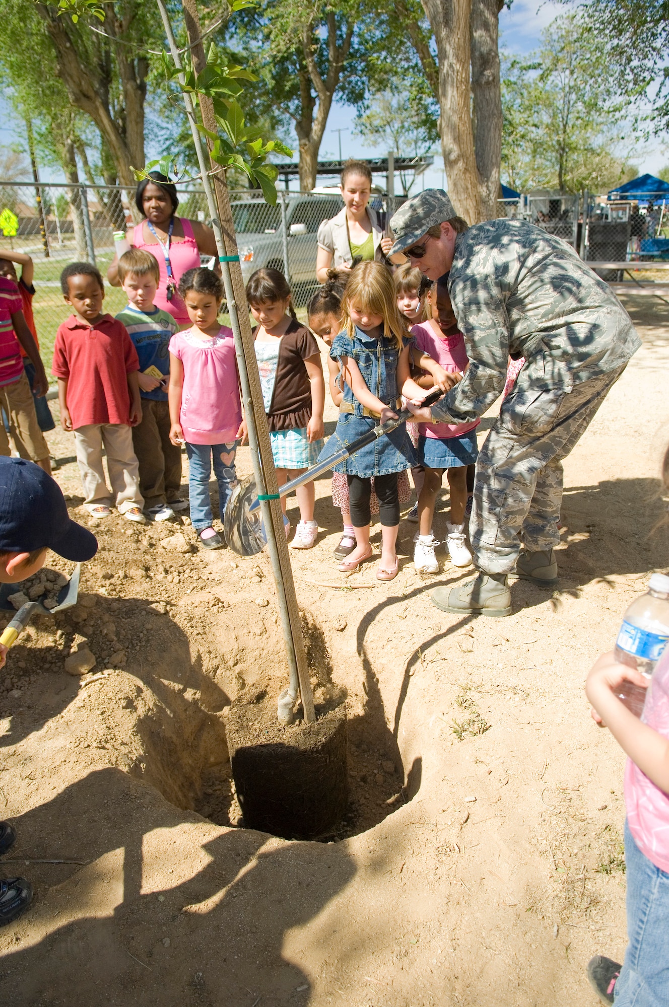 Col. Nancy Reeves-Flores, 95th Air Base Wing vice commander, together with base children, plants a tree during the Earth Day celebration here April 21. Environmental Management holds Earth Day every year to inform the community about the base's conservation efforts. (Air Force photo by Mike Cassidy)