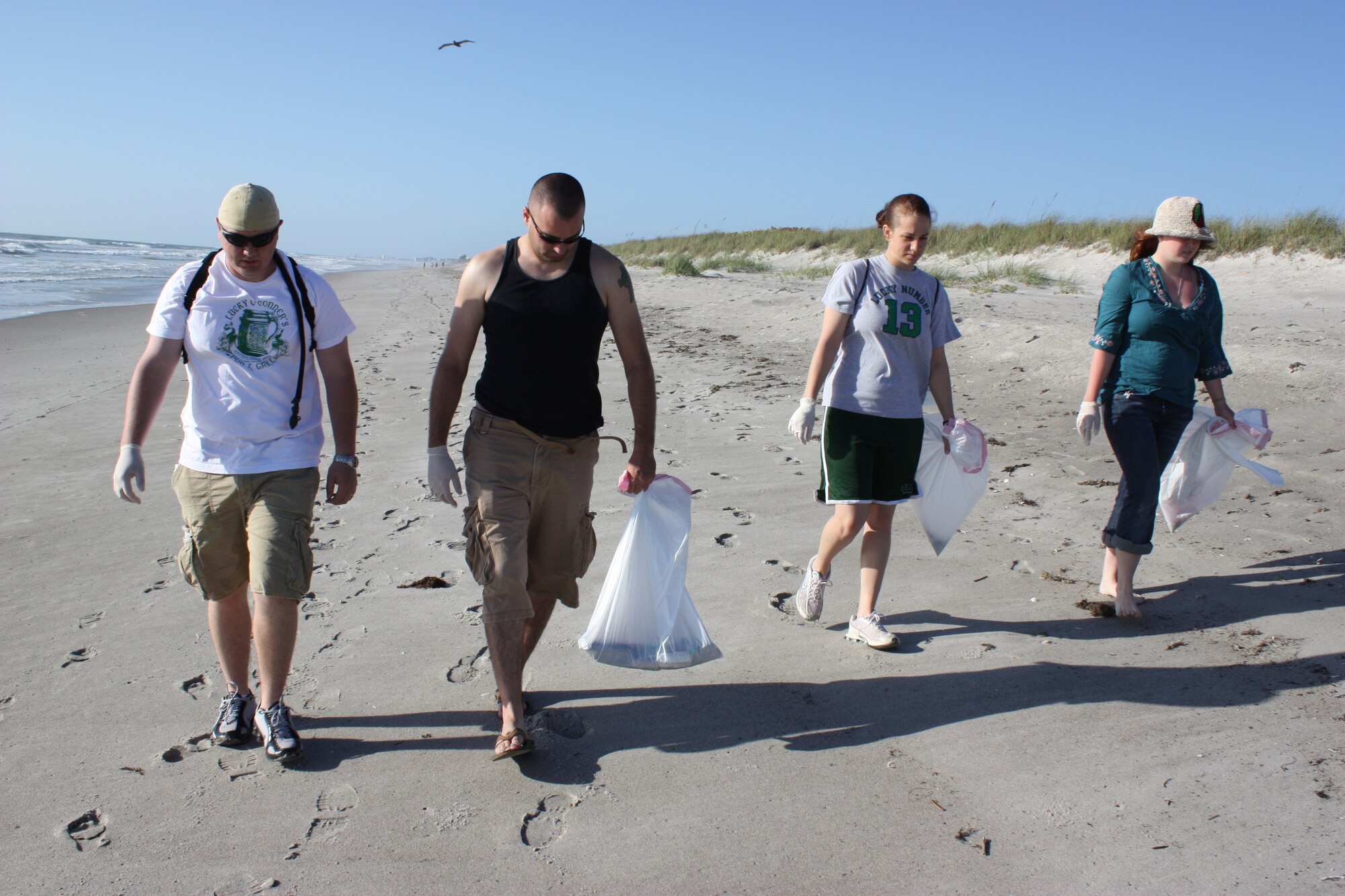 Staff Sgt. Jeremy Borromeo, Airman 1st Class Ken Cockriel, Senior Airman Jessica Dahmen and Airman 1st Class Kelly Fitzpatrick scan the sand for trash during the Patrick Air Force Base Beach Cleanup April 18. (U.S. Air Force photo/Airman 1st Class David Dobrydney)