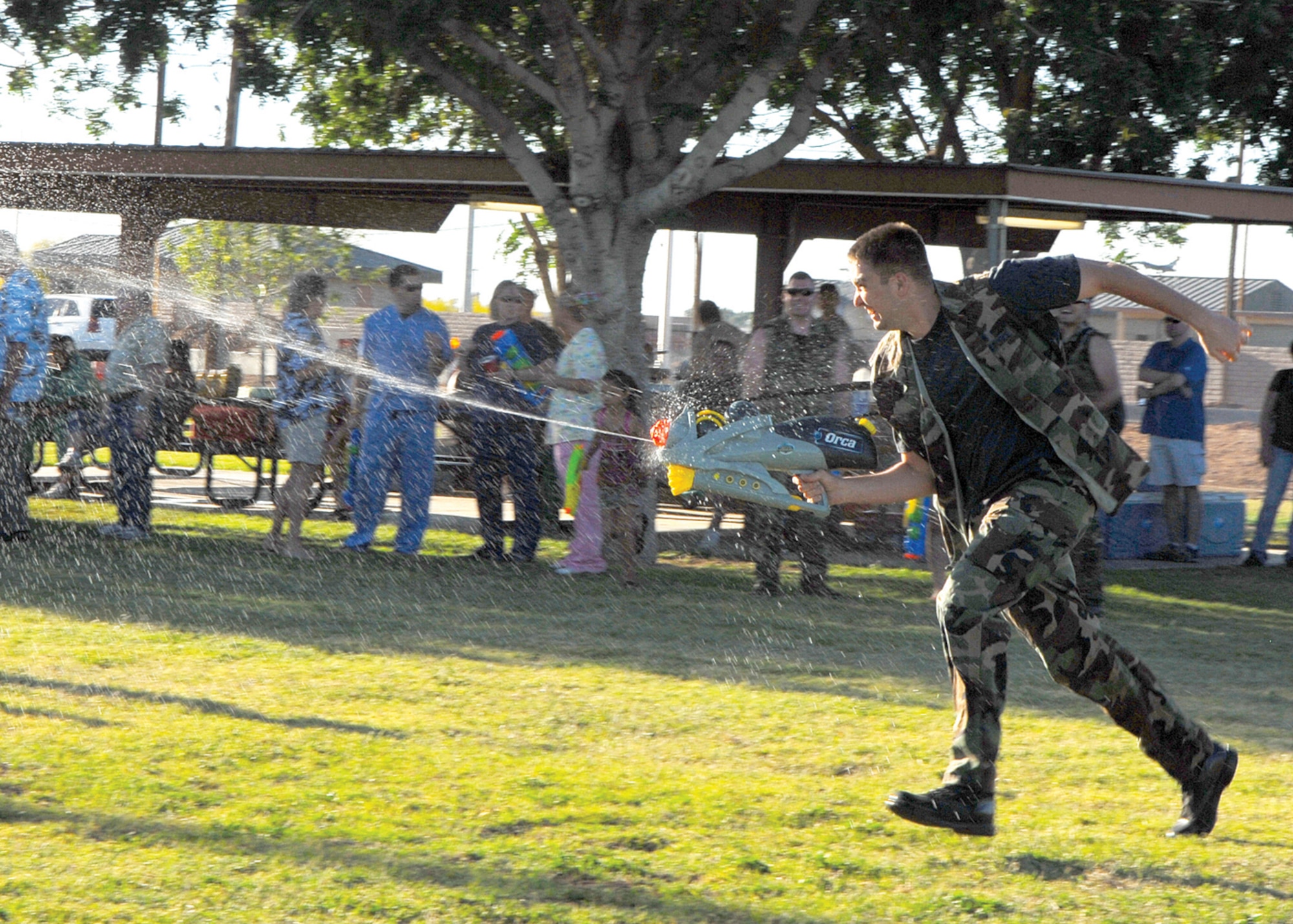 Staff Sgt. Robert Milush, 56th Aerospace Medicine Squadron public health journeyman, sprints across the field squirting water at children during the 56th Medical Group MASH Bash held at Fowler Park Saturday. (U.S. Air Force photo/Airman 1st Class Ronifel Yasay)