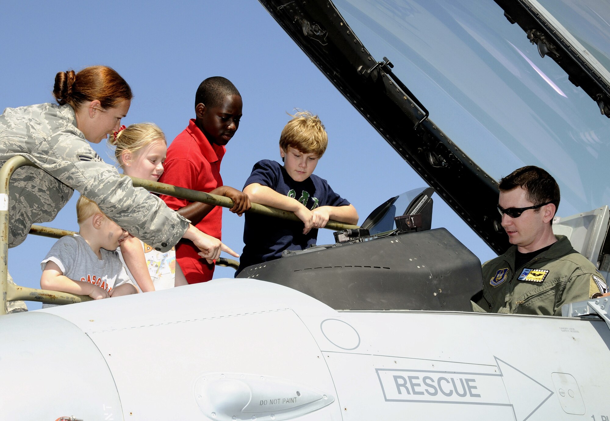1st Lt. Clifton Lemoine (right), 93rd Fighter Squadron pilot and Senior Airman Kristina Hewett, 93rd Fighter Squadron life support technician, give kids an up close and personal look at an F-16 fighter jet during “Bring your child to work day" at Homestead Air Reserve Base, Fla., on April 22. During the visit, service members assigned to the 482nd Fighter Wing, Special Operations Command South, U.S. Coast Guard Maritime Safety and Security Team, and Customs and Border Protection Air and Marine Branch provided a tour of the base, explained the inner workings of various weapons. (U.S. Air Force photo/Tim Norton)
