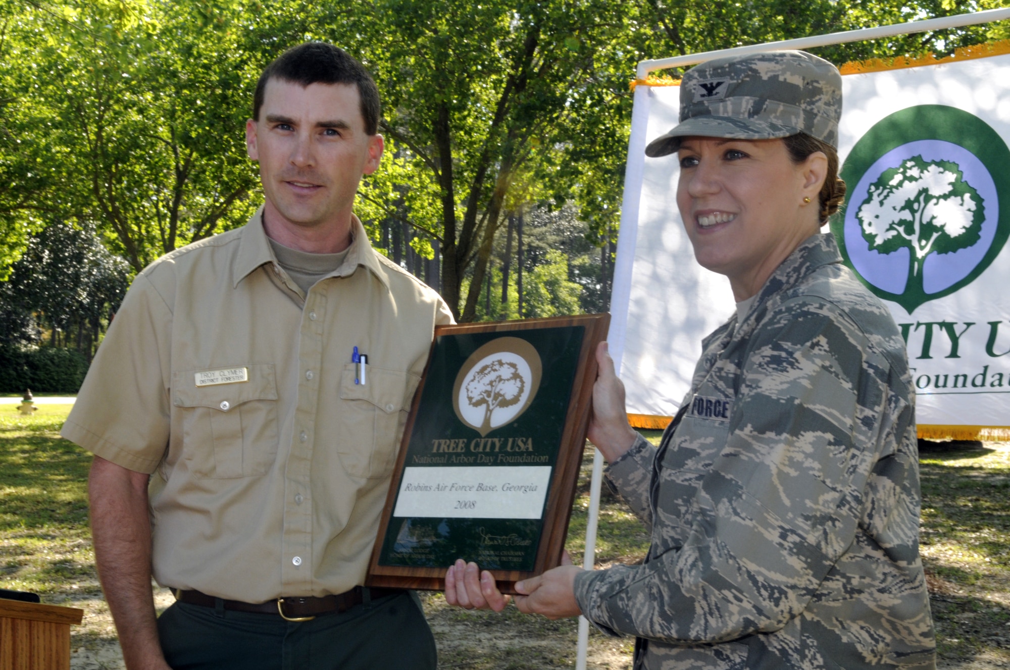 Troy Clymer, Georgia Forestry Commission, presents a plaque to Col. Debra Bean, 78th Air Base Wing vice commander, making Robins a Tree City USA. This is the 16th straight designation for Robins. U. S. Air Force photo by Sue Sapp