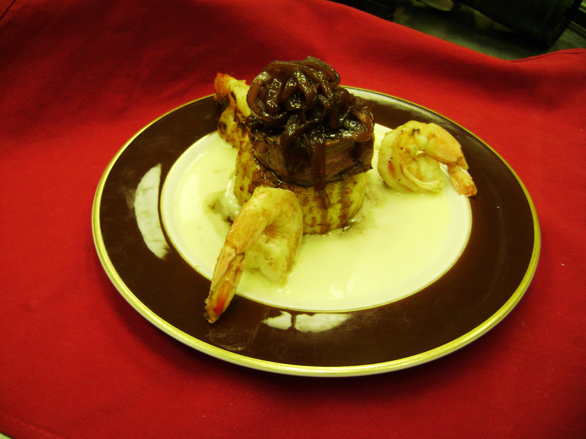 Filet mignon nestled in a bed of prawns, surrounded by a potato torte, red onion marmalade and steamed asparagus is served at the Sheppard Club April 17 during the Great Gatsby Gala: Fabulous French Feast. This is the beginning of many new events that will be held at the Sheppard Club. (U.S. Air Force/Rhonda Royer)

