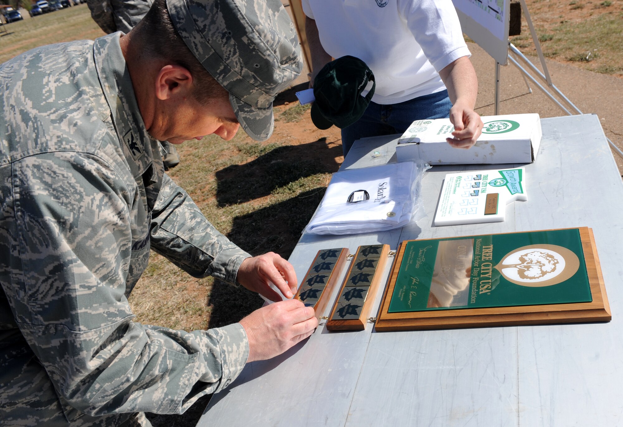 CANNON AIR FORCE BASE, N.M. -- Col. Ruedi Kaspar, 27th Special Operations Wing vice commander, pins a decal on the Tree City USA plaque at Doc Stewart Park here April 22. The Arbor Day Foundation recognized Cannon as a Tree City USA community for the 11th year in a row and presented Cannon with its first Growth Award. The 27th Special Operations Civil Engineer Squadron Natural Resources Management Flight hosted numerous  Arbor Day observance basewide, as well as a storytelling session for children at the Clovis Carter Public Library April 23.(U.S. Air Force Photo/Airman 1st Class Evelyn Chavez)