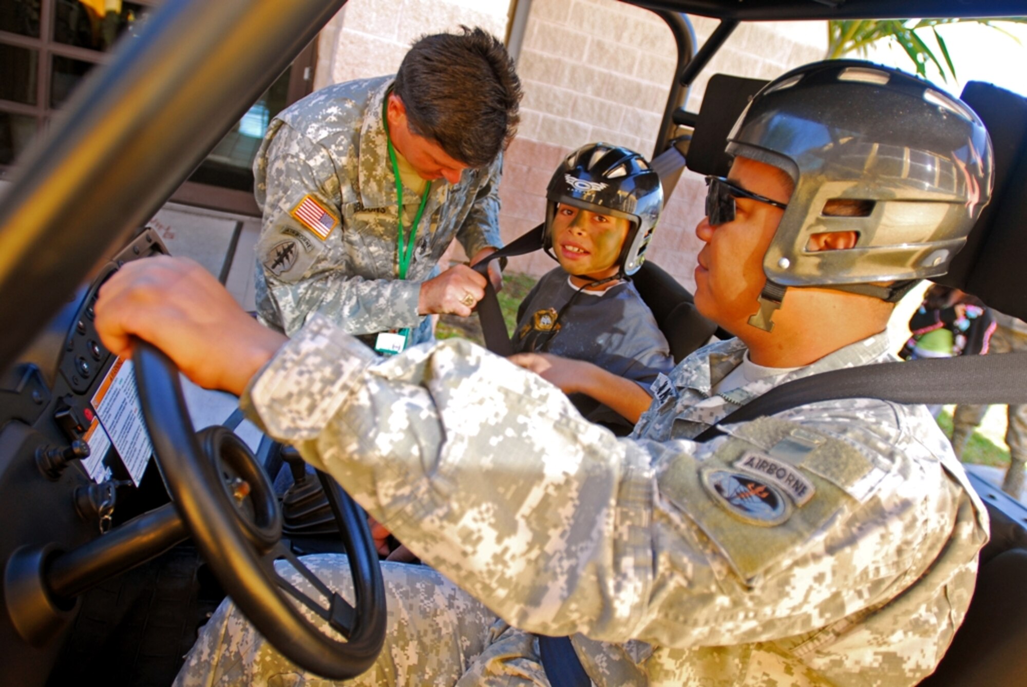 1st Sgt. Willie Gibbons, Special Operations Command South, ensures the safety of Edwin Figueroa by buckling him before going for a ride on a "Spec Ops" vehicle during "Bring your child to work day" at Homestead ARB, FL. (U.S. Army Photo by Sgt. 1st Class Felix A. Figueroa, SOCSOUTH PAO)