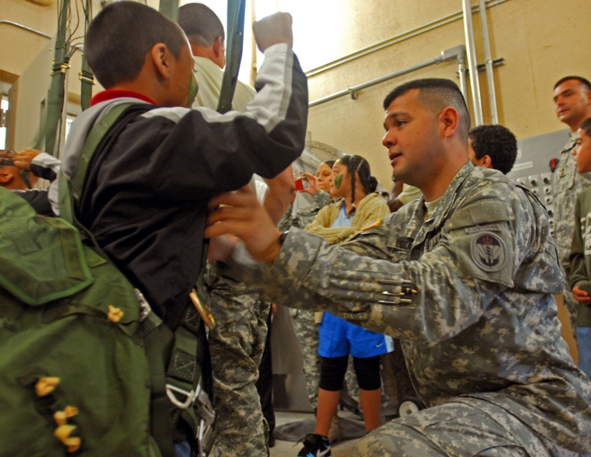 Chief Warrant Officer Luis Lozano, Special Operations Command South, helps rig a child into a parachute harness during "Bring your child to work" day at Homestead ARB, FL recently. (U.S. Army Photo by Sgt. 1st Class Felix A. Figueroa, SOCSOUTH PAO)